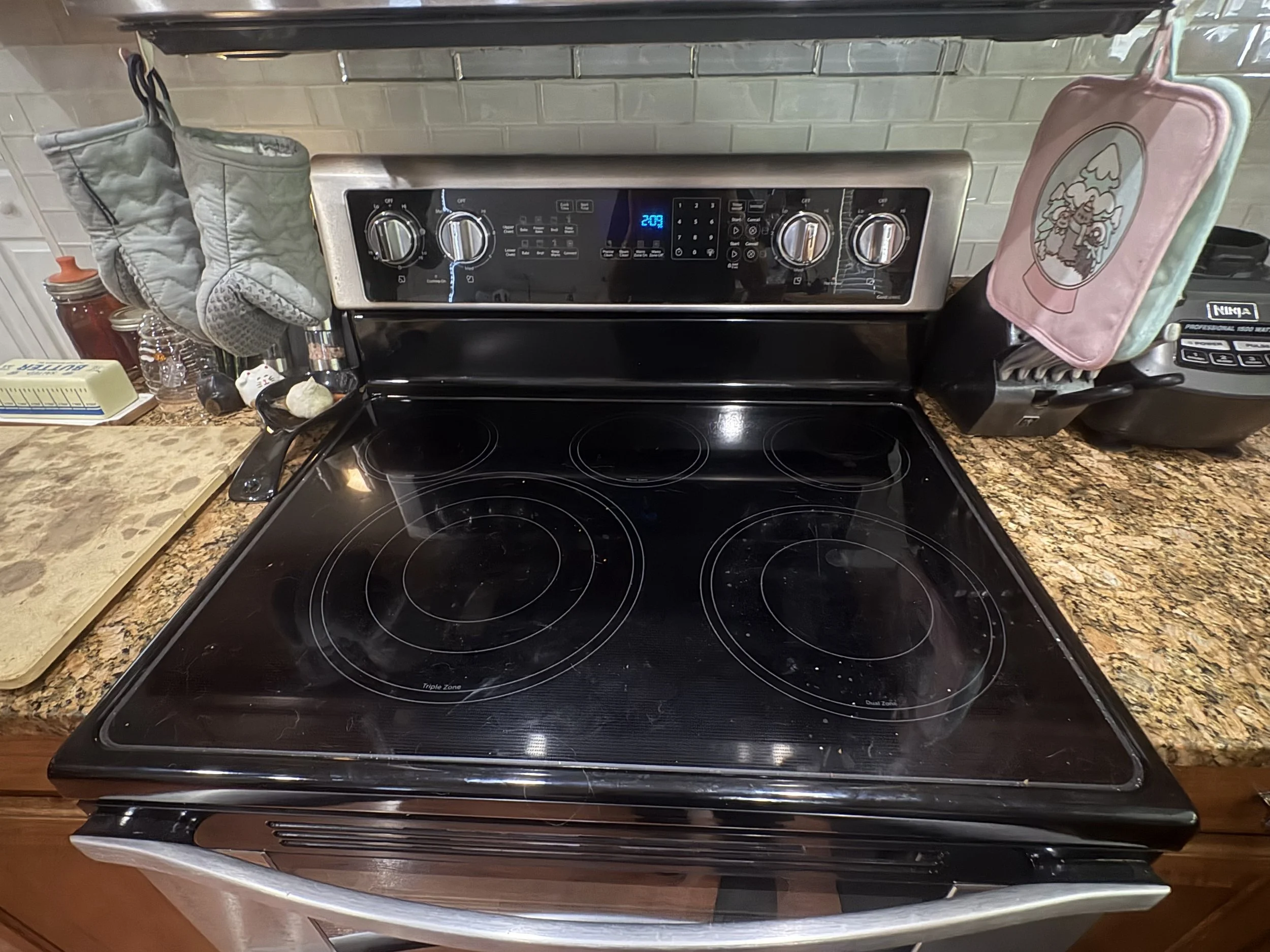 Black glass-top electric range with four burners and digital controls in a kitchen