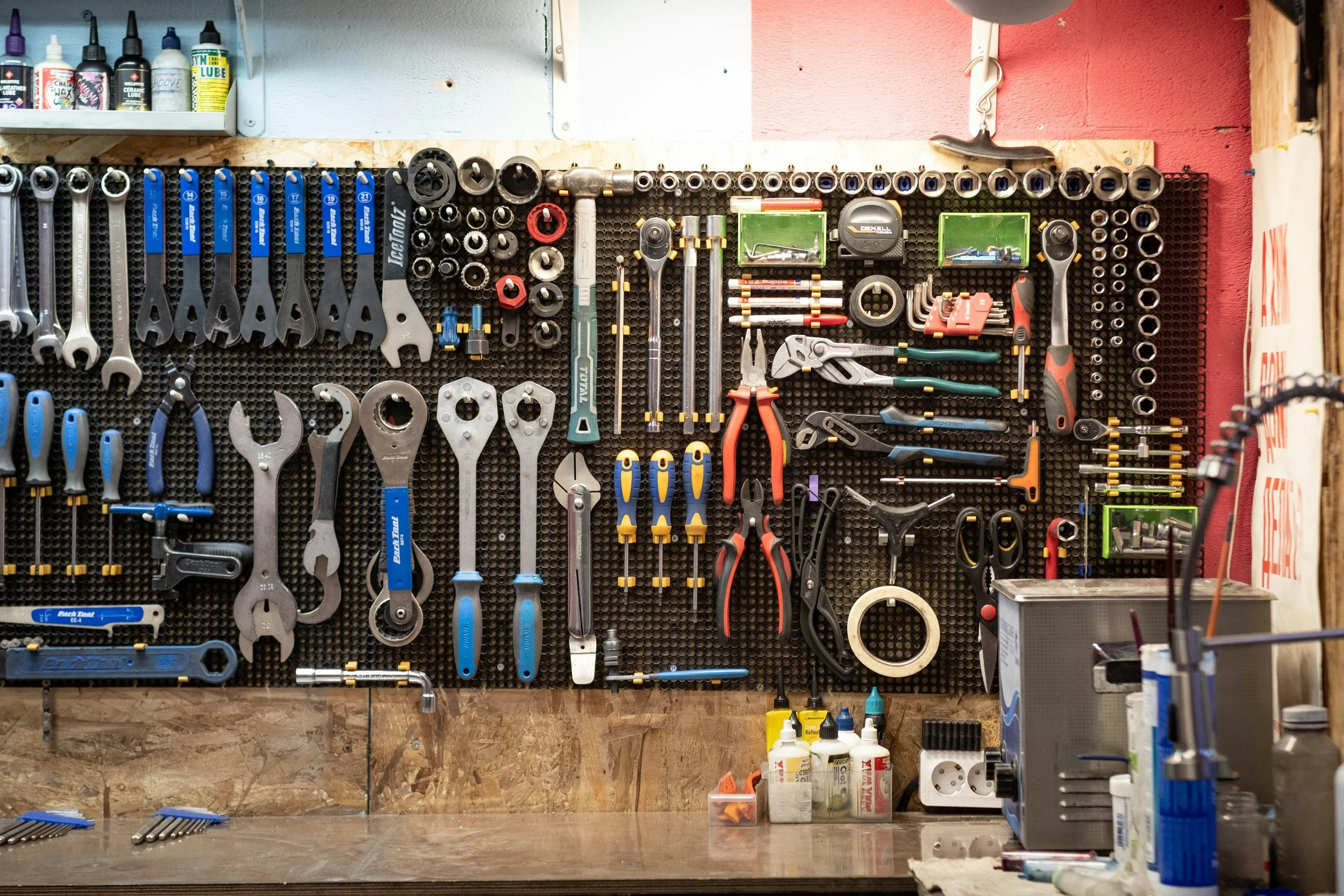 Organized workshop tool wall displaying wrenches, sockets, ratchets, pliers, screwdrivers, hex keys, and other automotive tools.