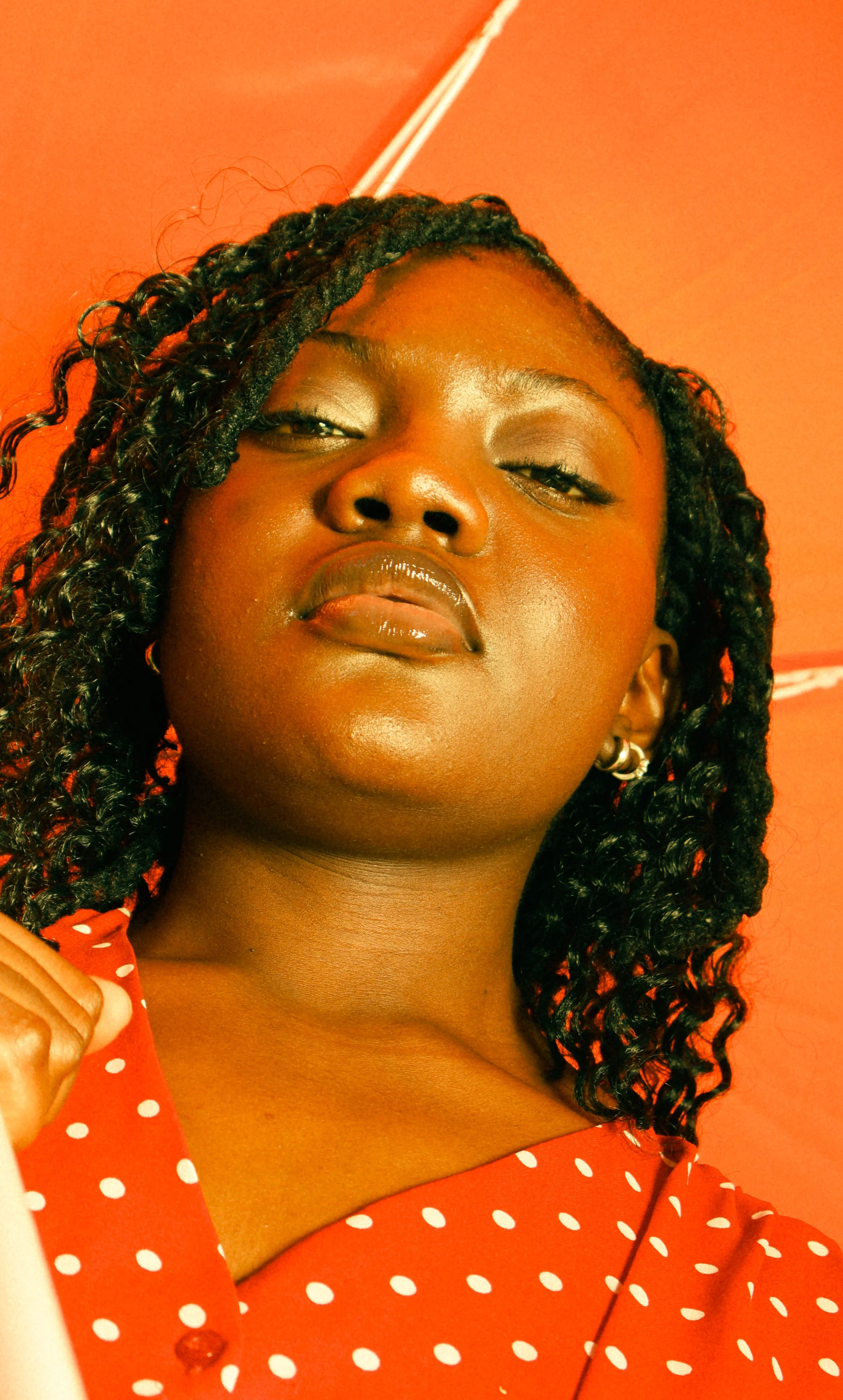 An editorial portrait photograph of Jane Simataa covered by a red umbrella taken by Kim Kambinda in Windhoek, Namibia..