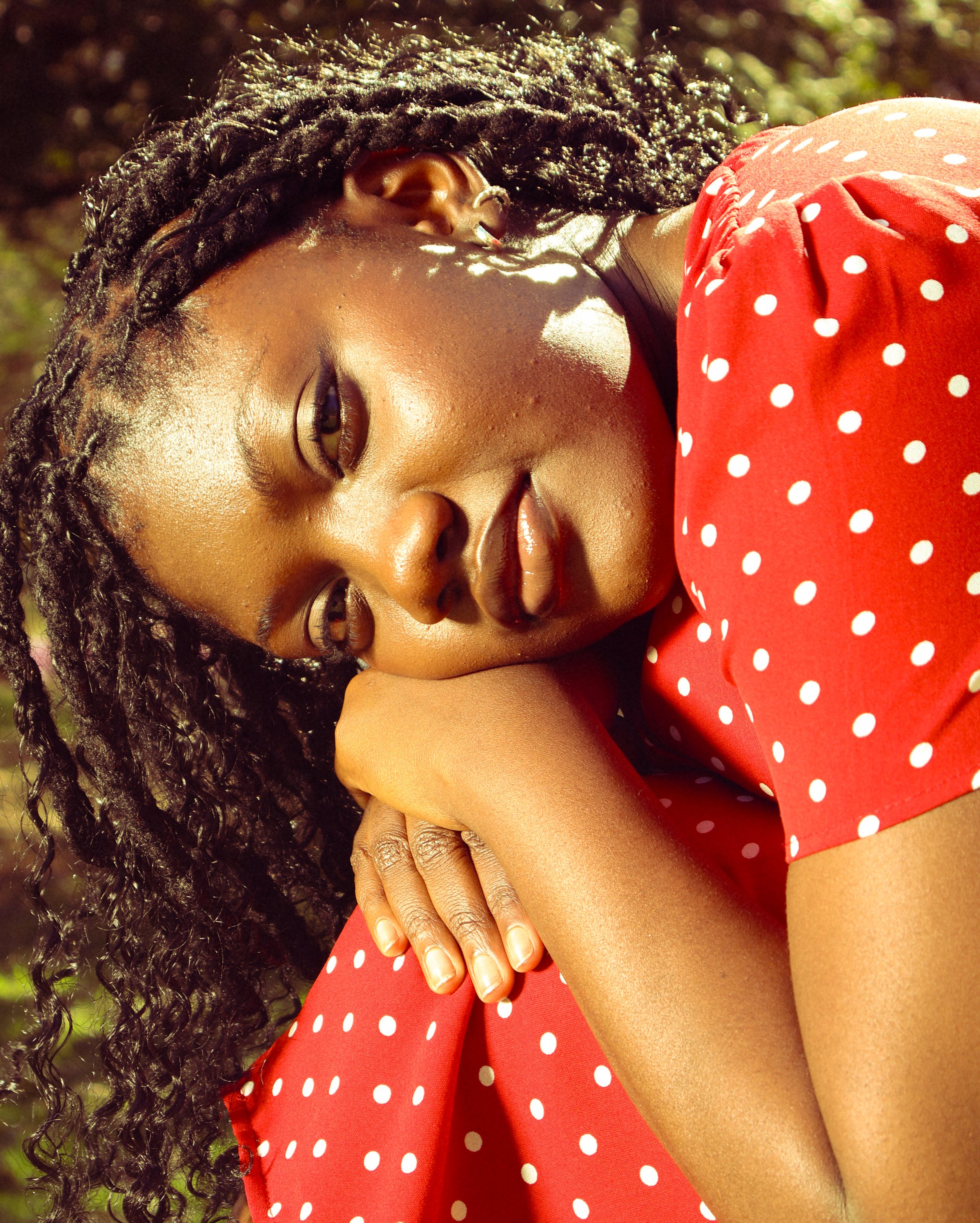 An editorial portrait photograph of Jane Simataa staring at the camera while resting her head on her legs taken by Kim Kambinda in Windhoek, Namibia.