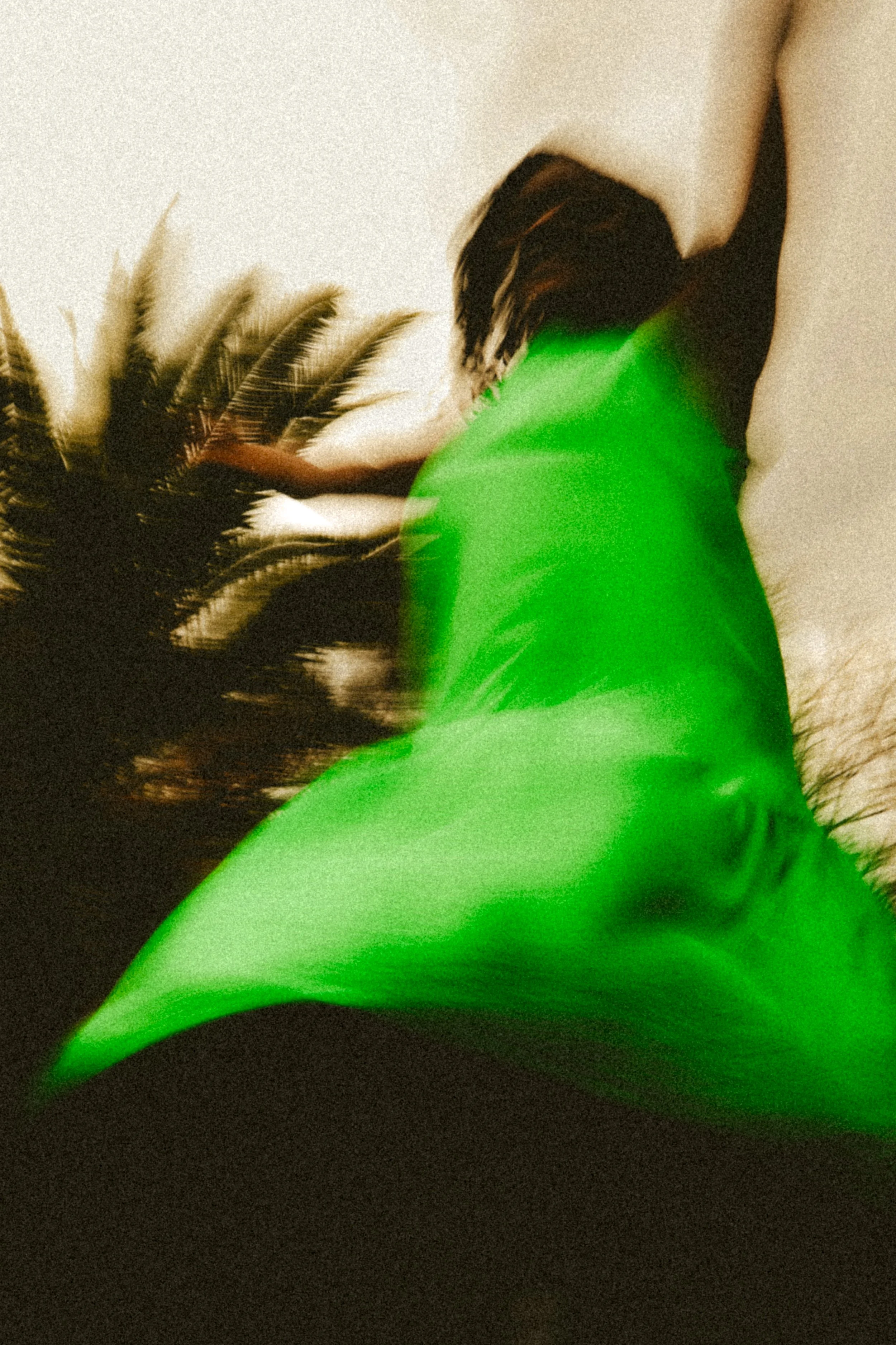 A blurry editorial portrait photograph of Jane Simataa twirling around in a green dress taken by Kim Kambinda in Windhoek, Namibia.