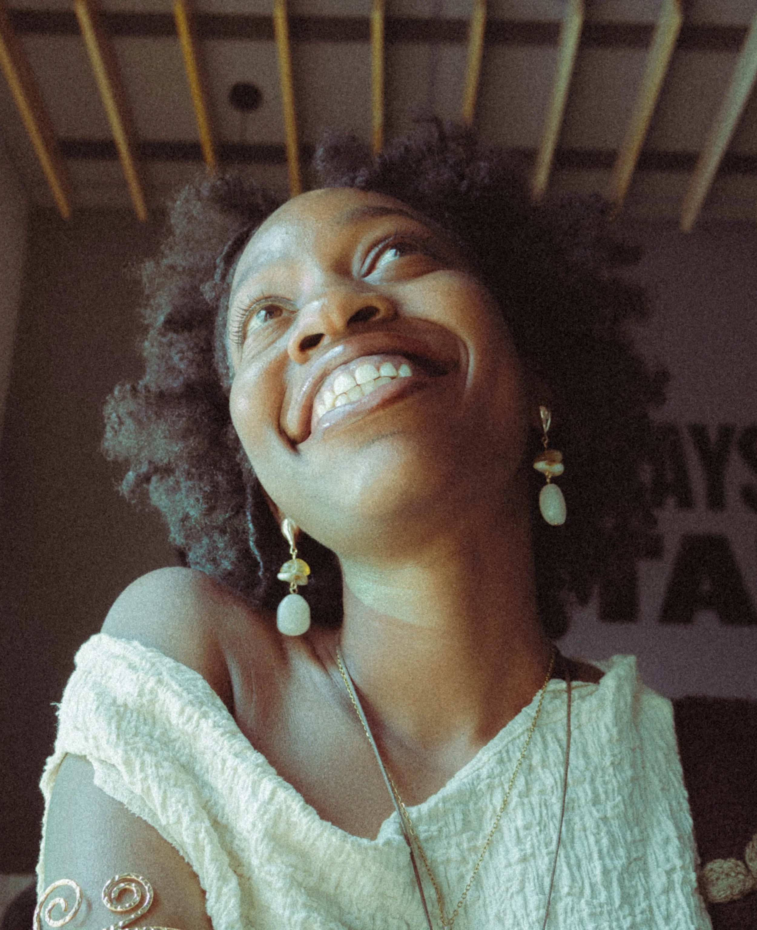 An editorial portrait photograph of a woman looking up and smiling taken by Kim Kambinda in Windhoek, Namibia.