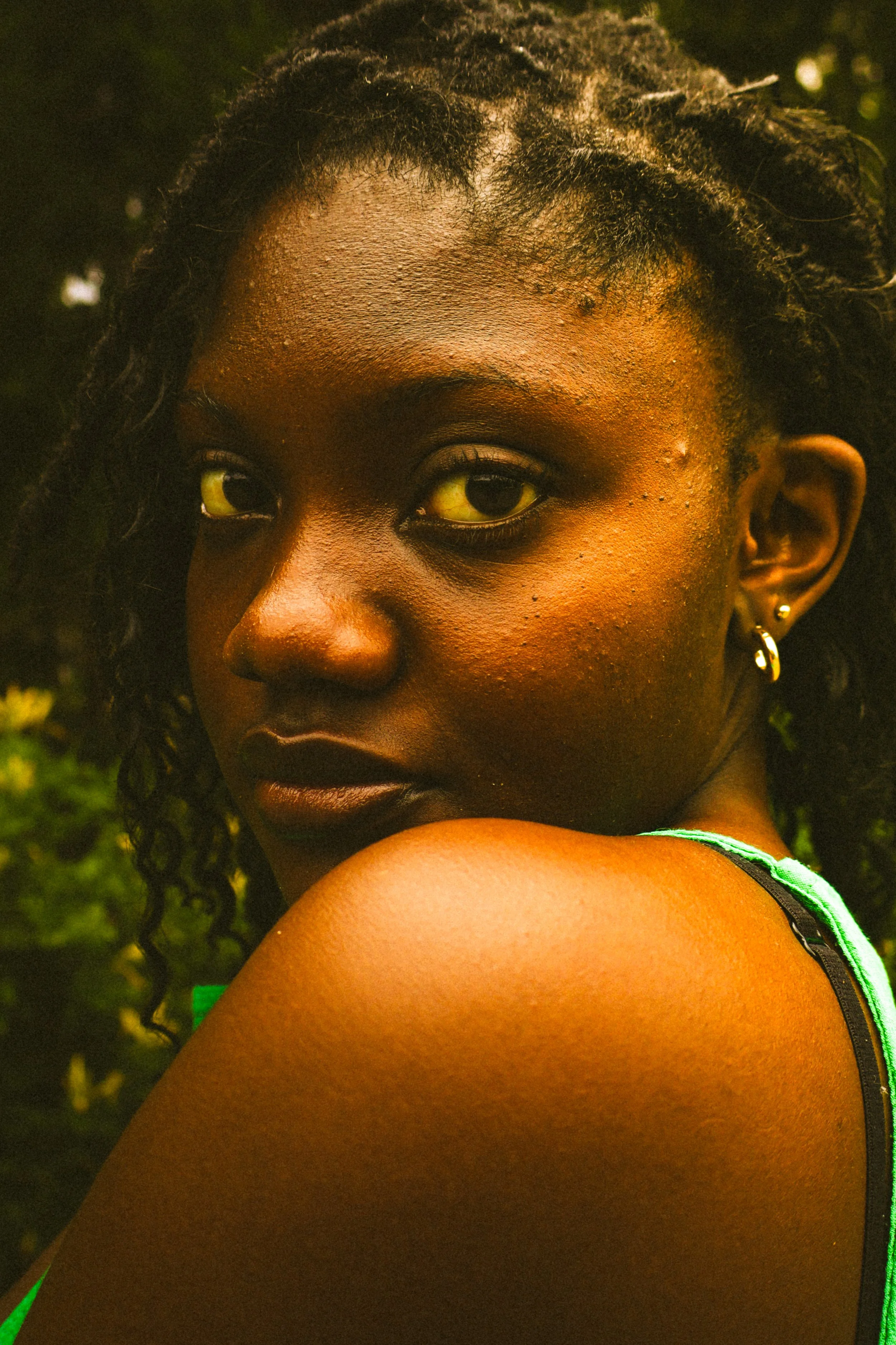 An editorial portrait photograph of Jane Simataa staring at the camera slightly covered by her shoulder taken by Kim Kambinda in Windhoek, Namibia.