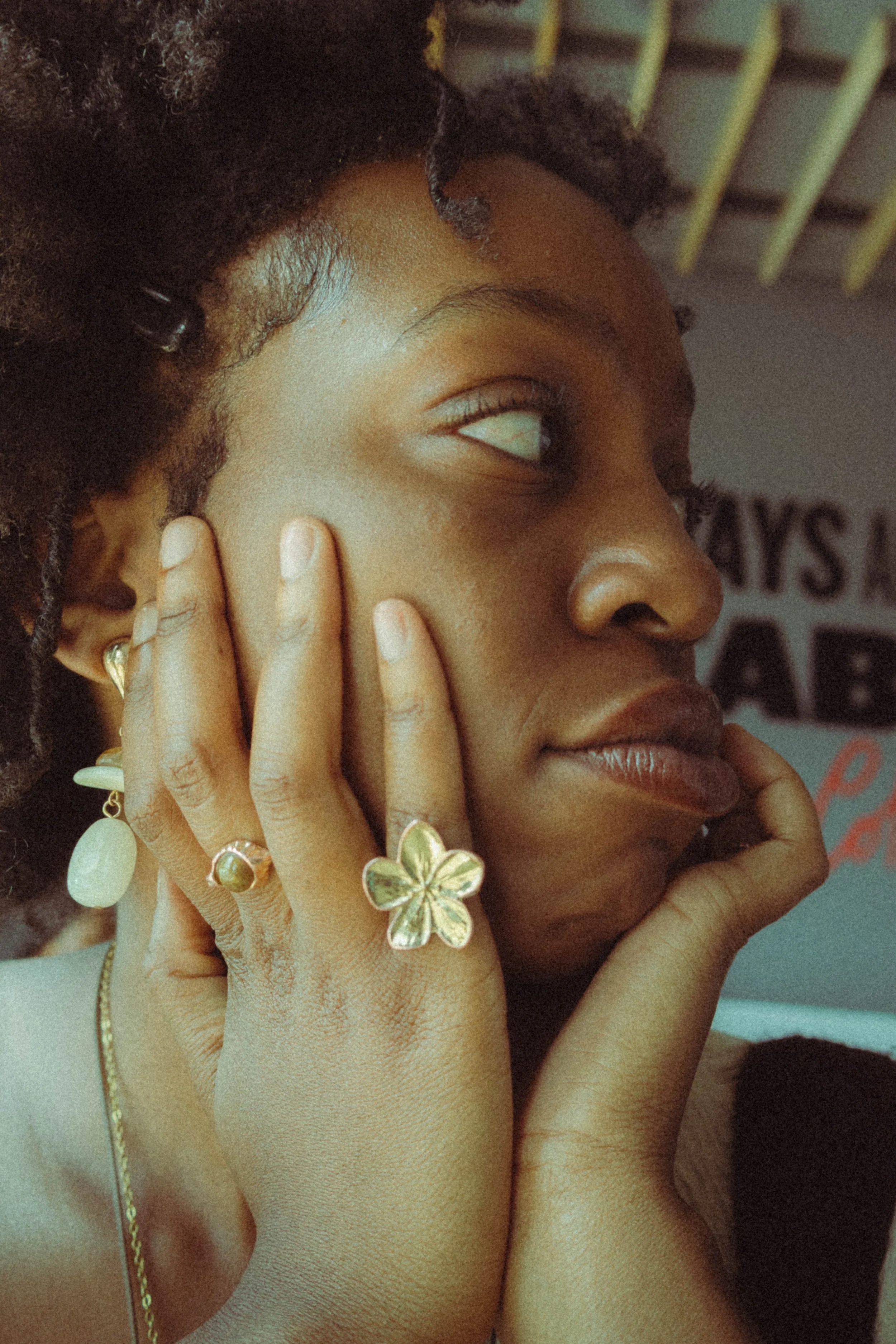 An editorial portrait photograph of a woman looking to her right with her hands touching her face taken by Kim Kambinda in Windhoek, Namibia.
