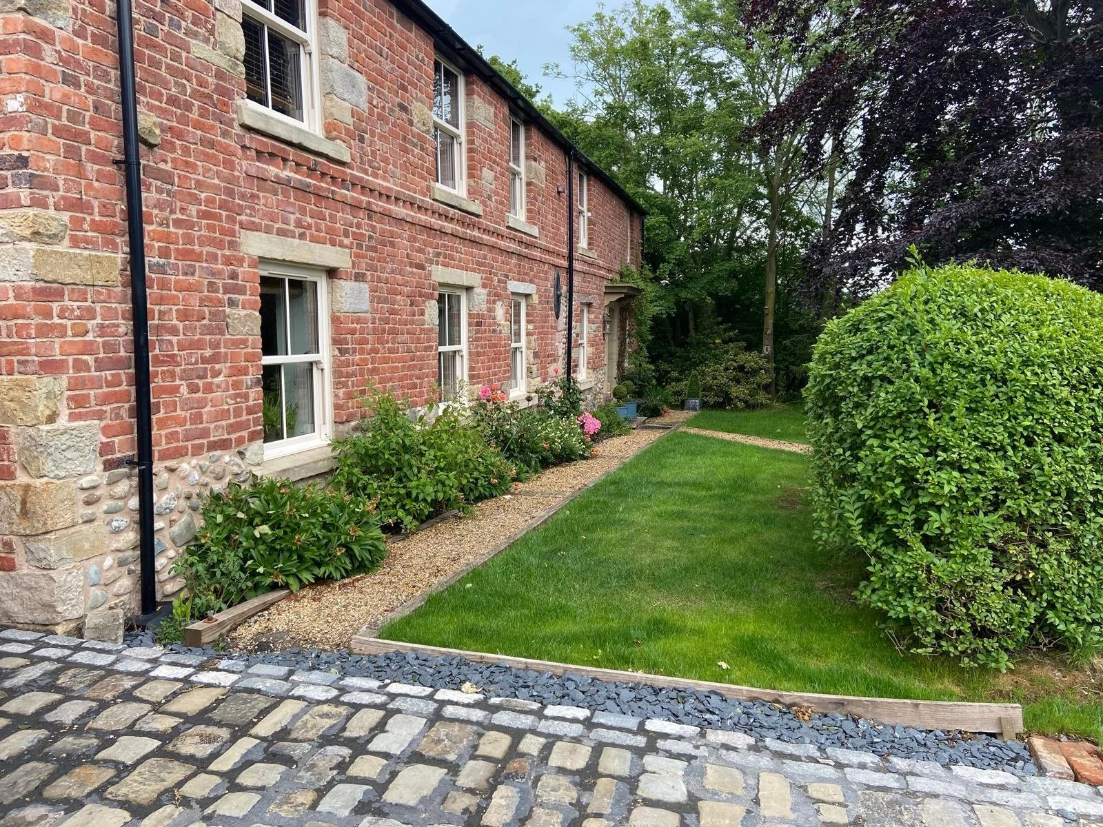 aCobbled edging and new lawn laid beside a brick cottage