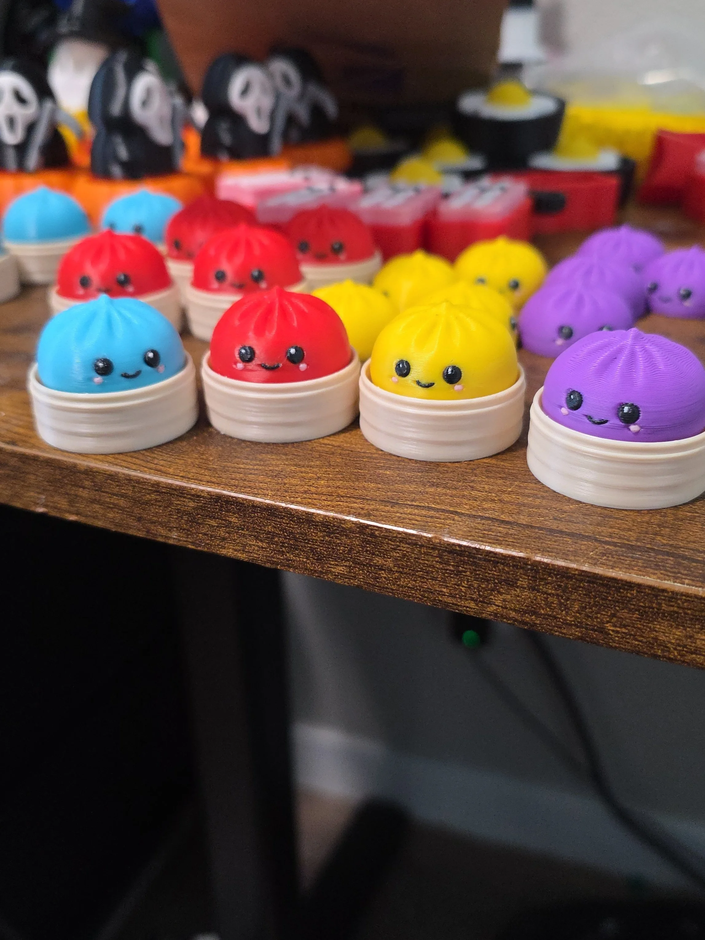 Colorful small toys resembling cute, smiling dumplings in red, yellow, blue, and purple colors, placed on a wooden surface.