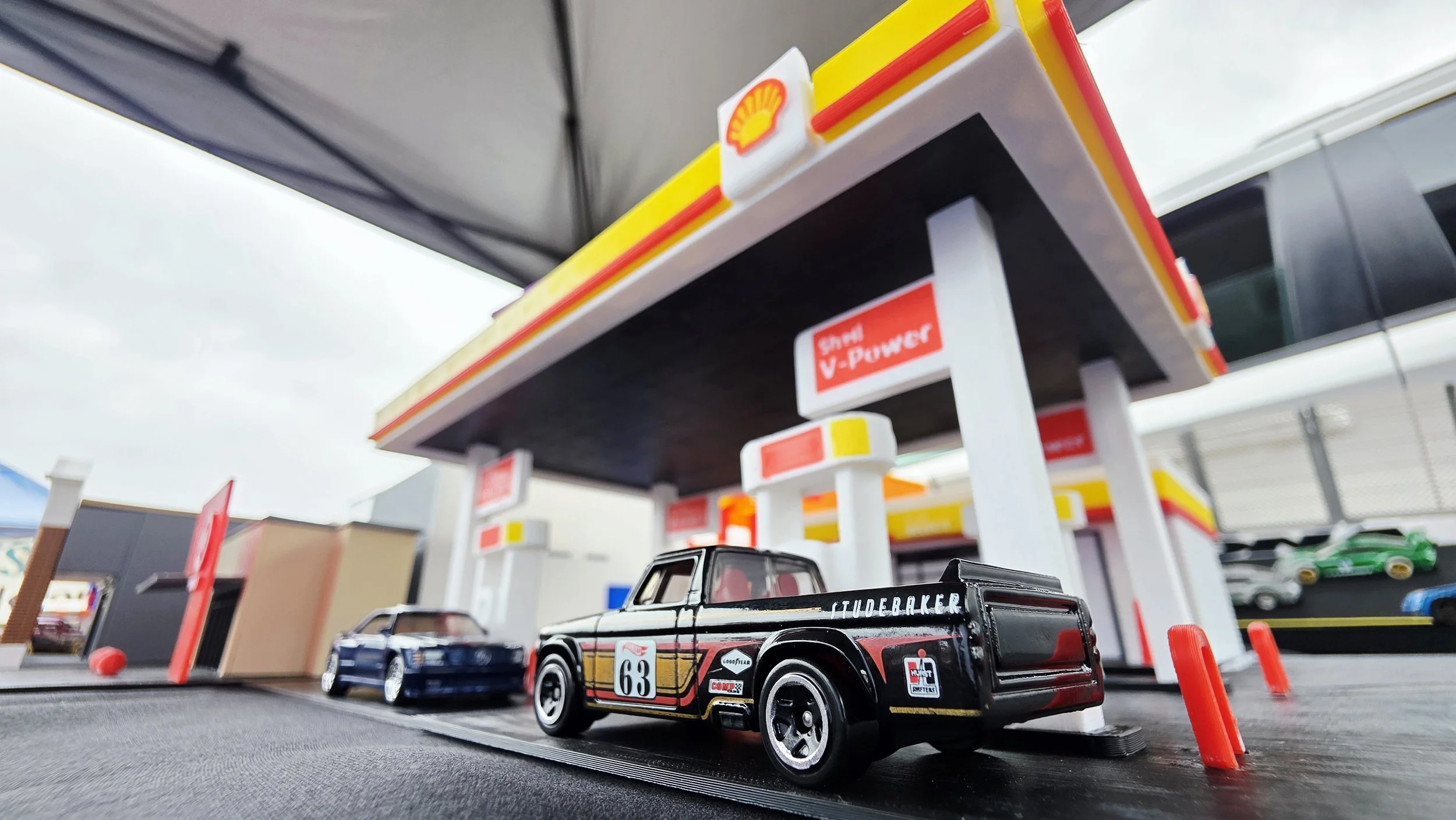Toy model cars at a Shell gas station scene.