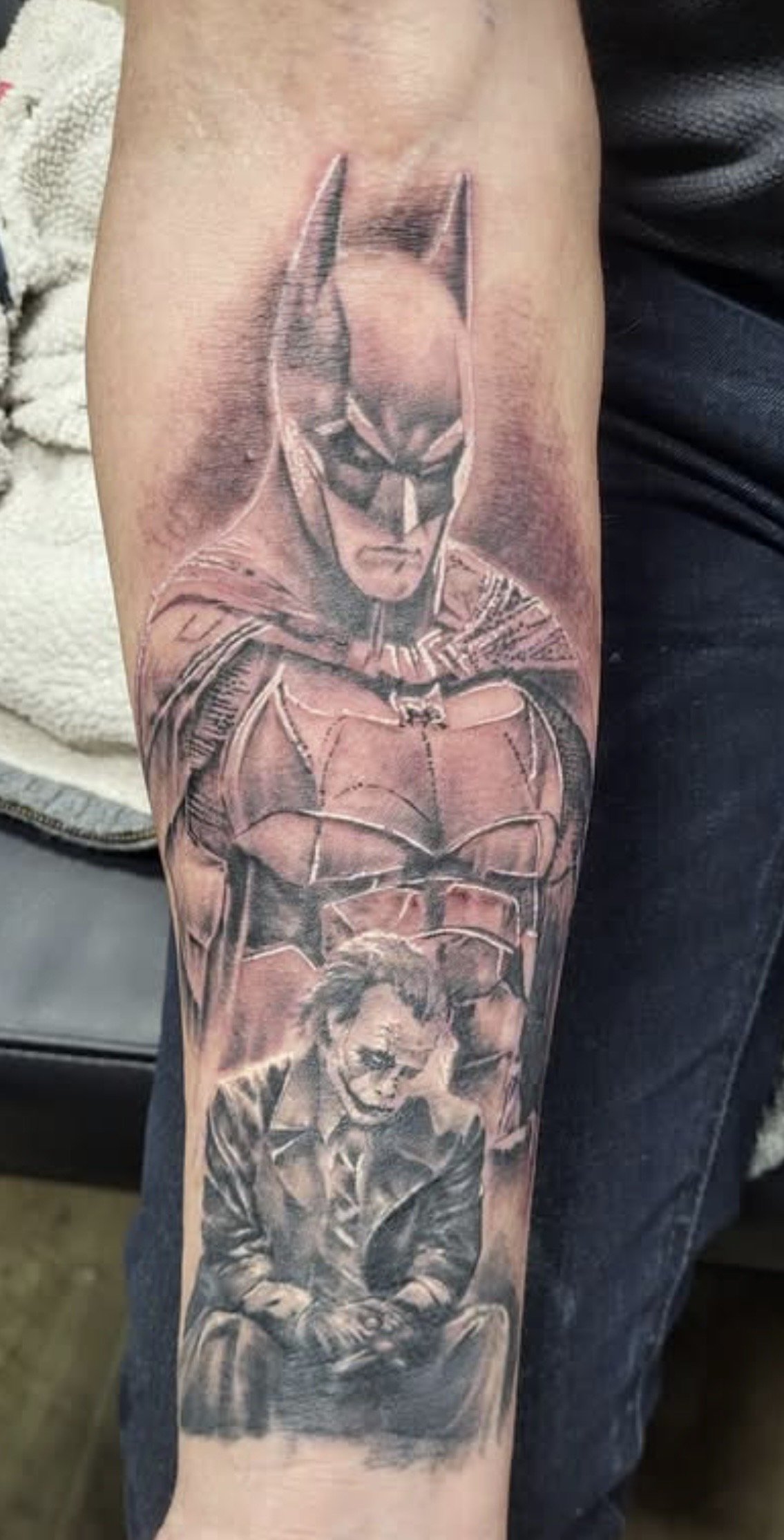 Detailed Batman and Robin comic-style tattoo covering a person’s forearm.