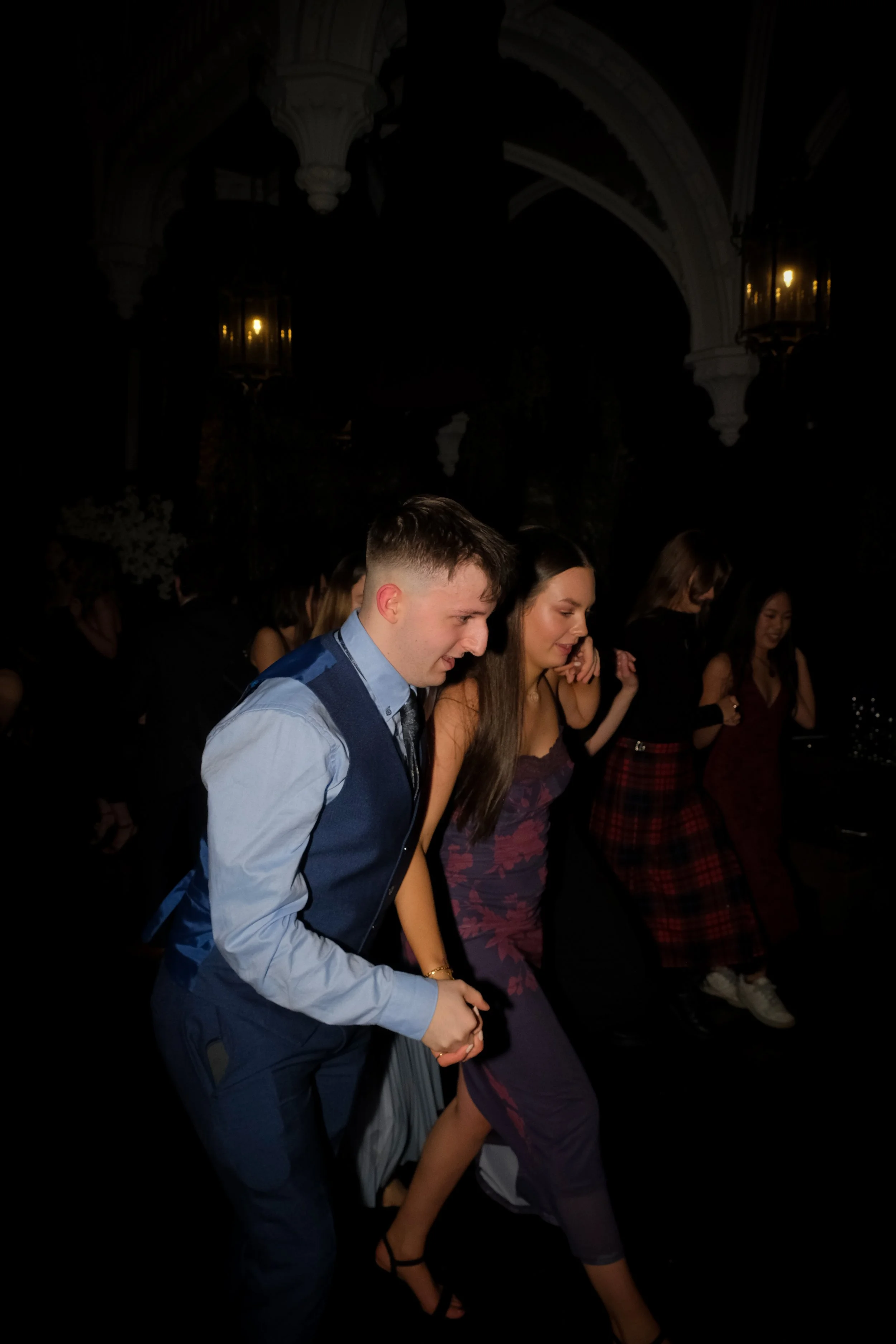 People dancing at a party or event in a dimly lit setting.
