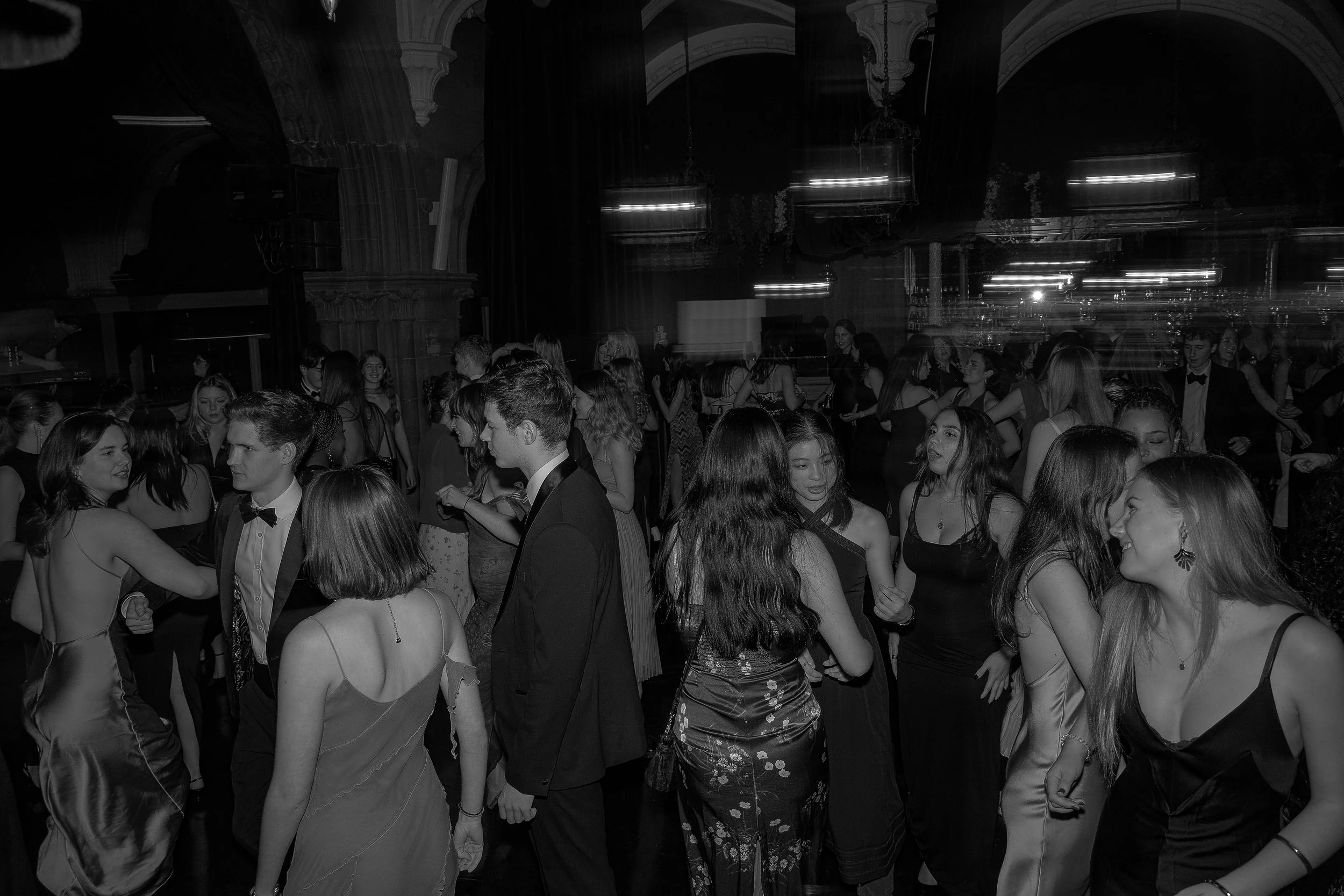 People dancing and socializing at a formal event or dance party in an elegant hall.