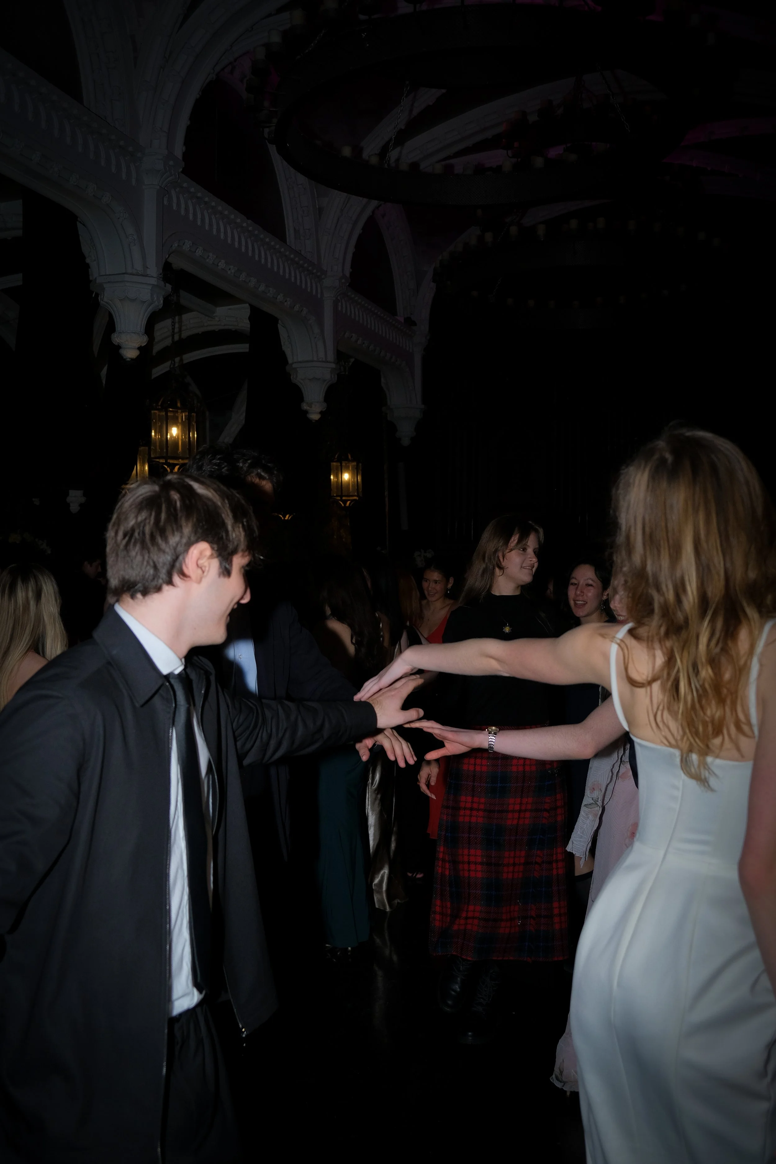 People dancing at a dance party or social event in a decorated venue with ornate arches and lanterns.