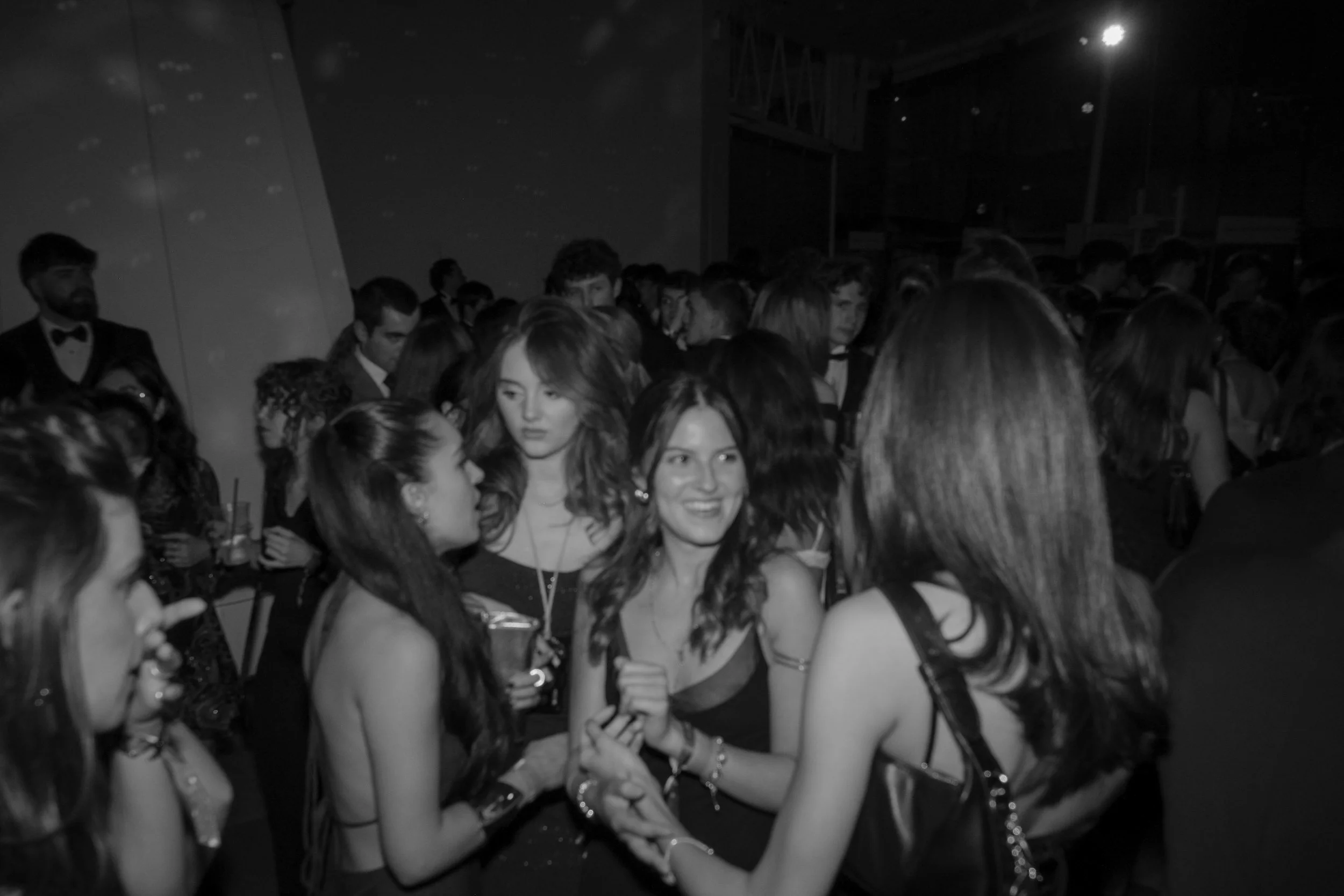 People at a social event or party, dressed in formal attire, engaging in conversation amidst a crowd.
