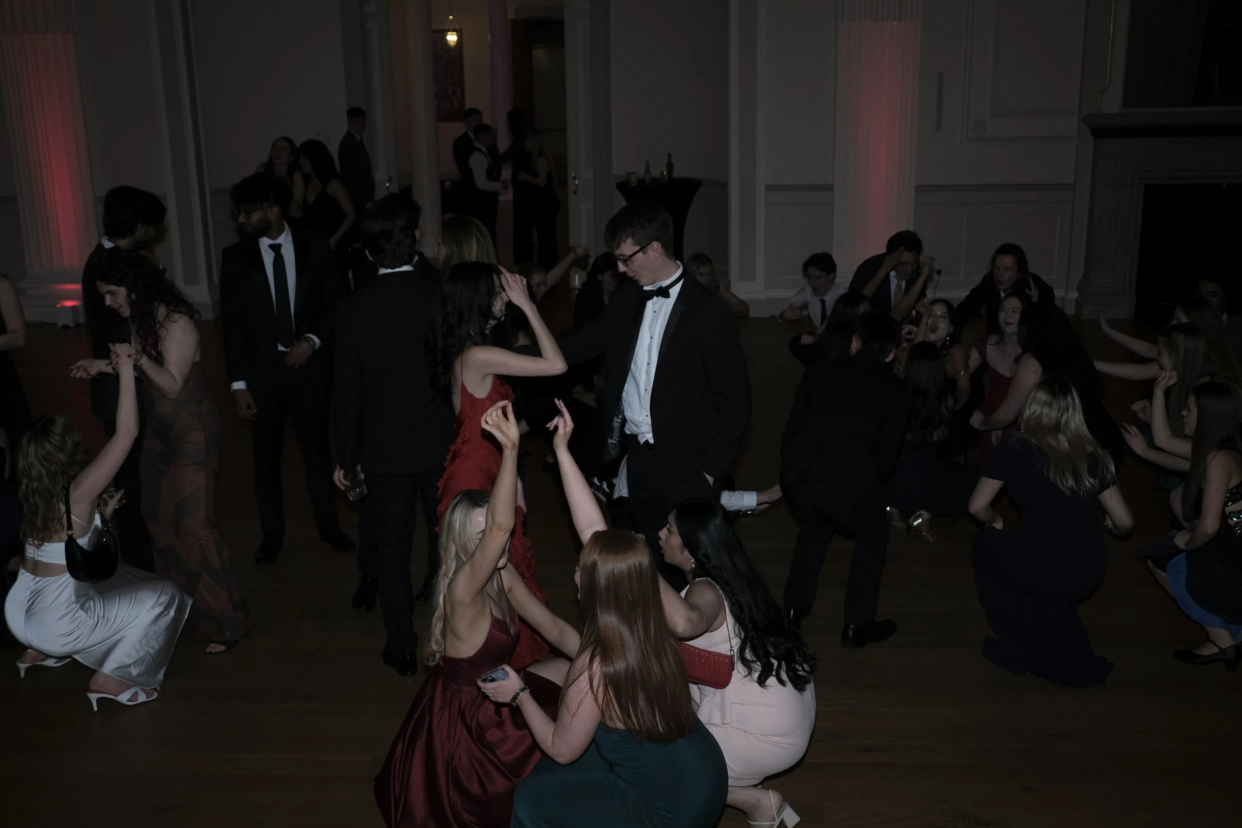 People dancing and socializing at a formal event or party in a large, elegant room.