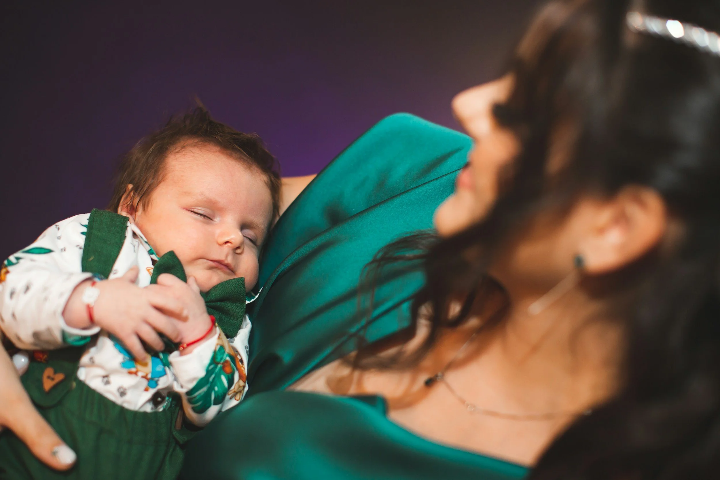 Mother holding a sleeping newborn baby in a patterned outfit