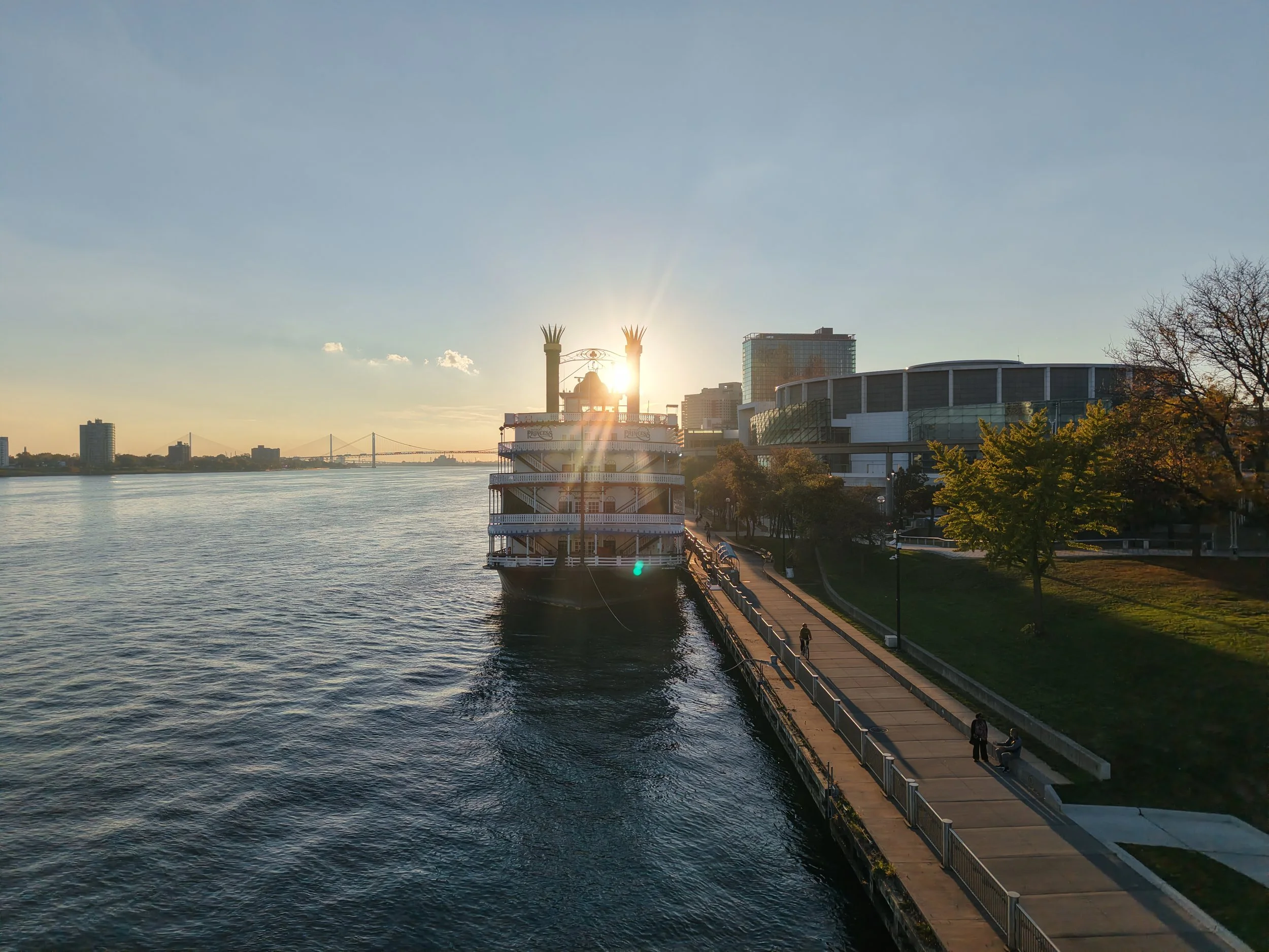 Sunset view of the Detroit Riverwalk with the riverboat Princess docked beside the waterfront promenade and city skyline