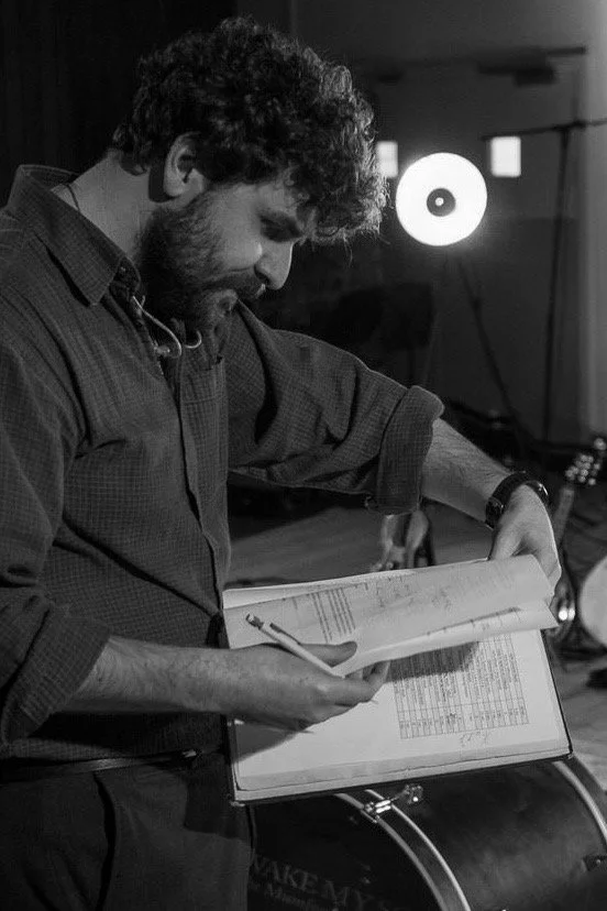 Samuel Freeman reading sheet music beside staging in a theatre space.