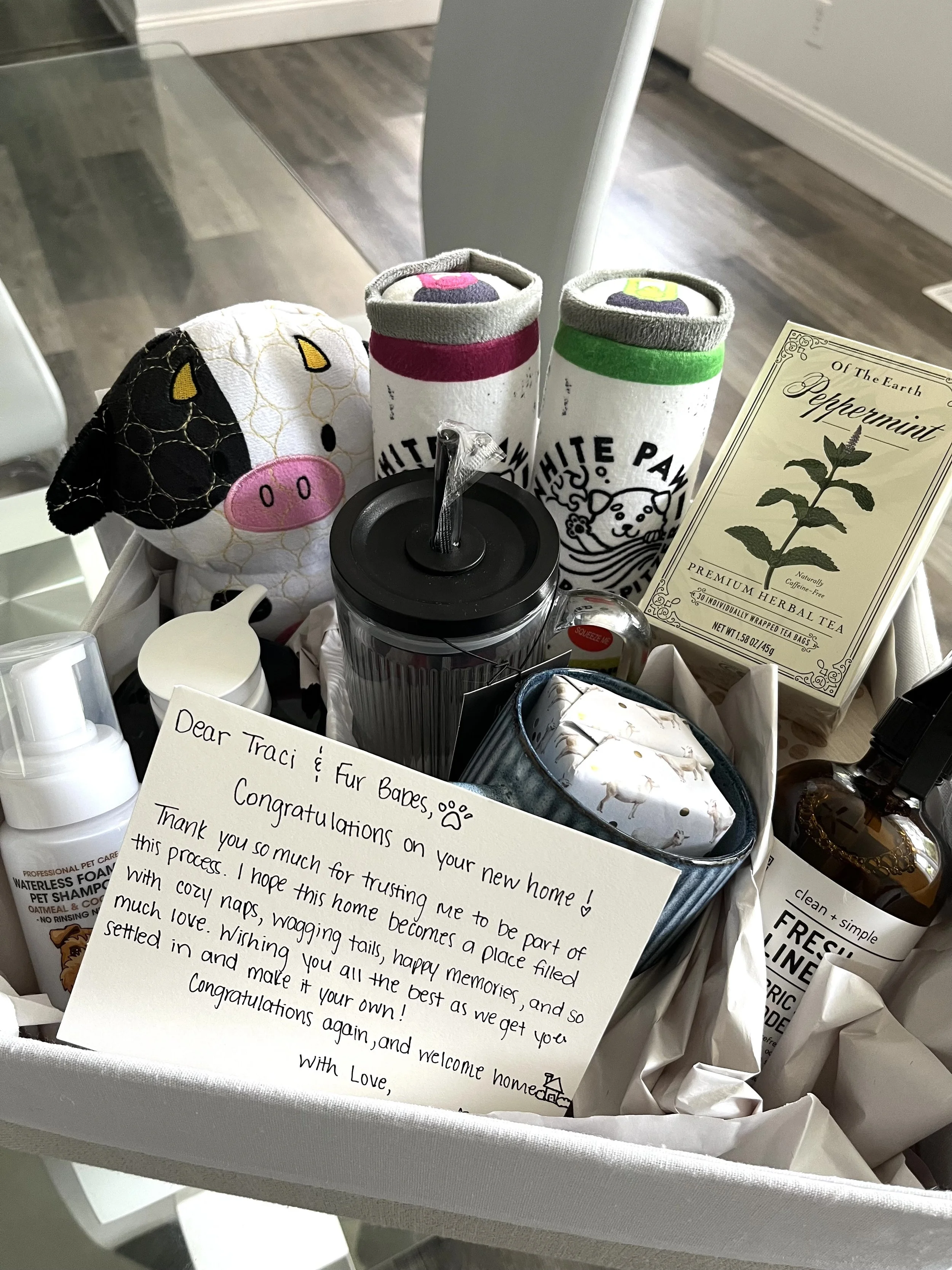 Gift basket filled with pet toys, grooming supplies, herbal tea, treats, and a handwritten congratulations card.