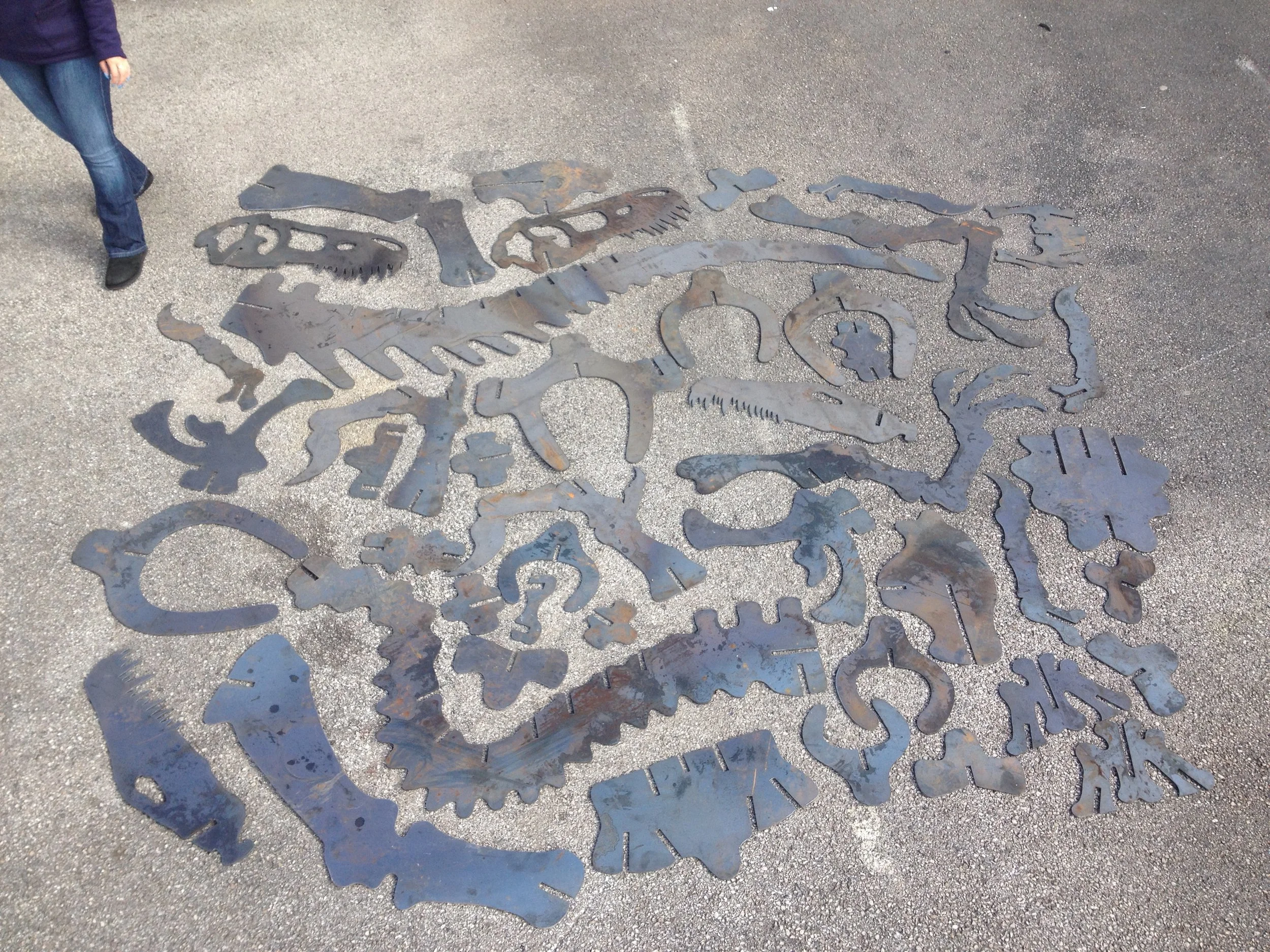 Giant Raptor dinosaur CNC plasma cut steel components laid out before assembly into a 10ft high by 16ft long slot-together metal model, manufactured by PlazCutz Ltd.