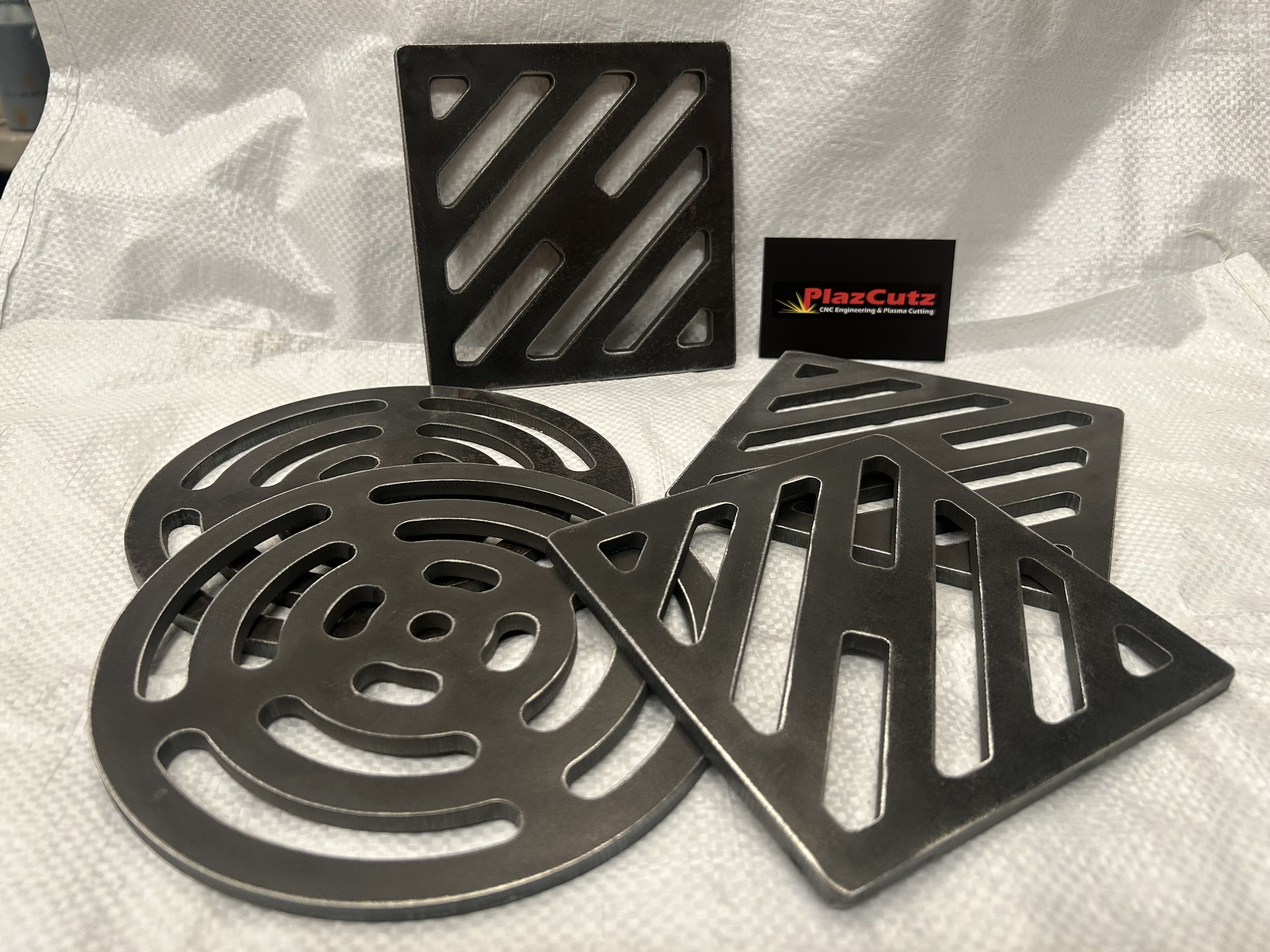 Heavy-duty steel drain covers manufactured by PlazCutz, available in square and round designs.