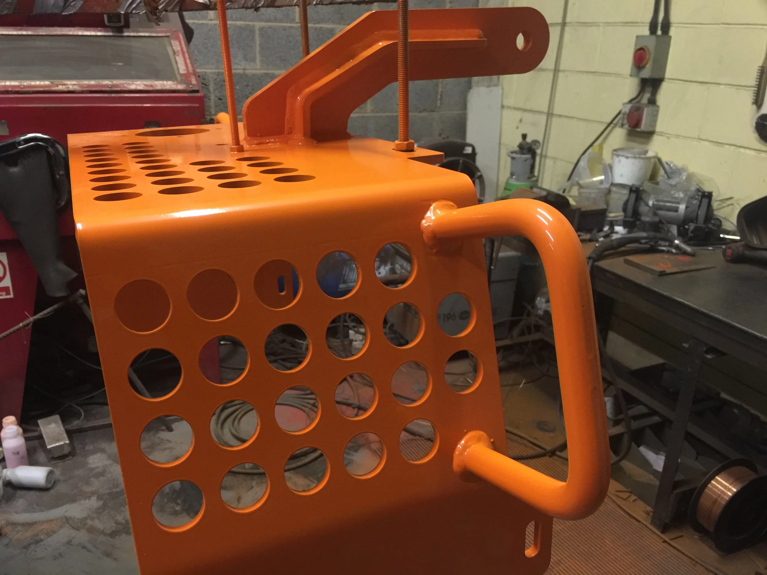 Custom subsea equipment chassis frame finished in gloss orange powder coating by PlazCutz in Morecambe, Lancashire, showing the perforated steel panels, welded construction and mounting brackets.