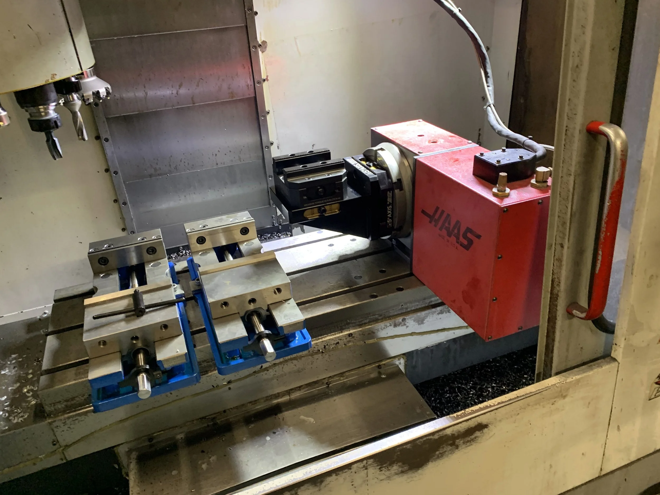 PlazCutz Haas VF2 CNC milling machine showing the fourth-axis rotary unit and precision machining vices inside our engineering workshop in Morecambe, Lancashire.
