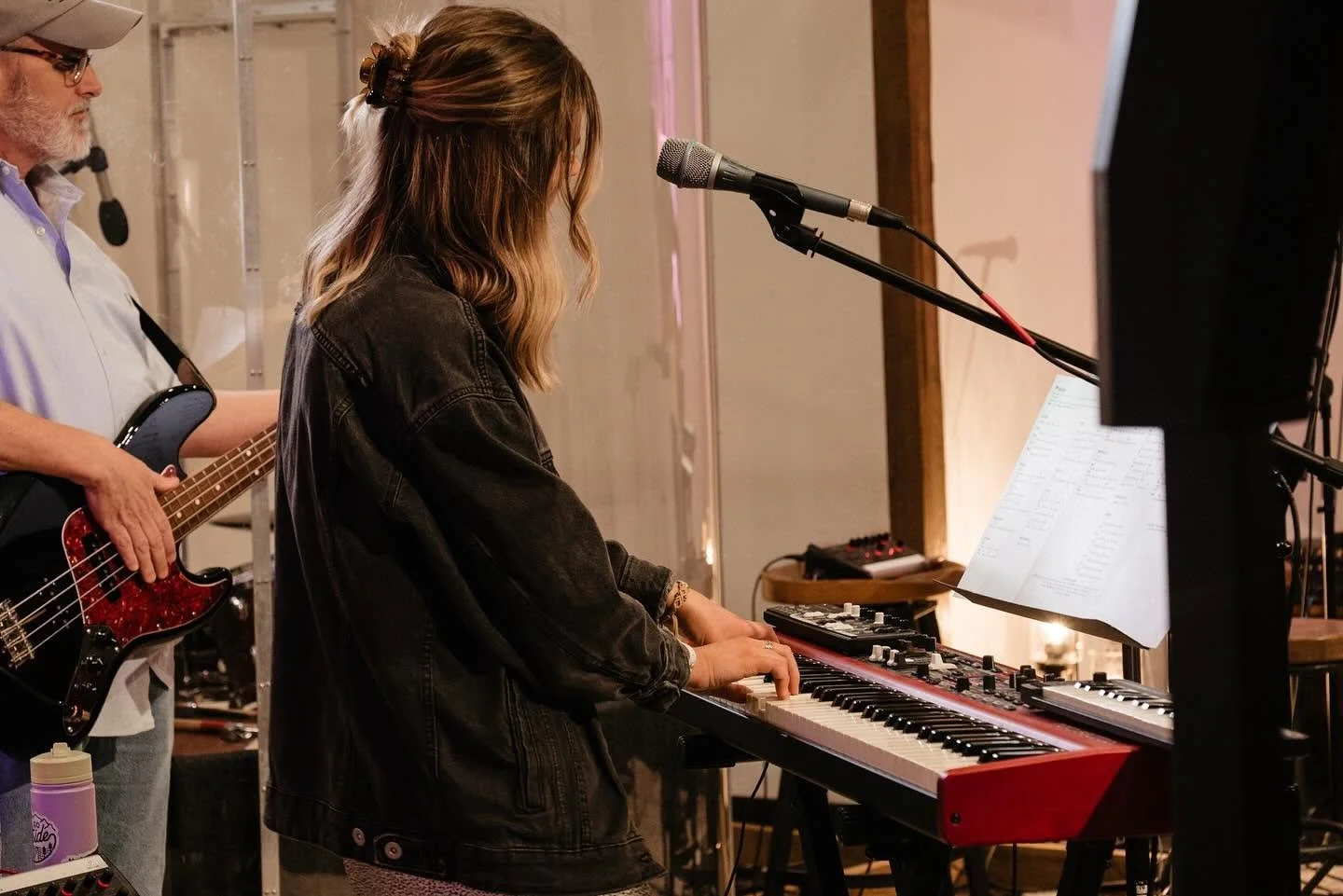 Singer playing a red electronic keyboard beside a bassist during a rehearsal