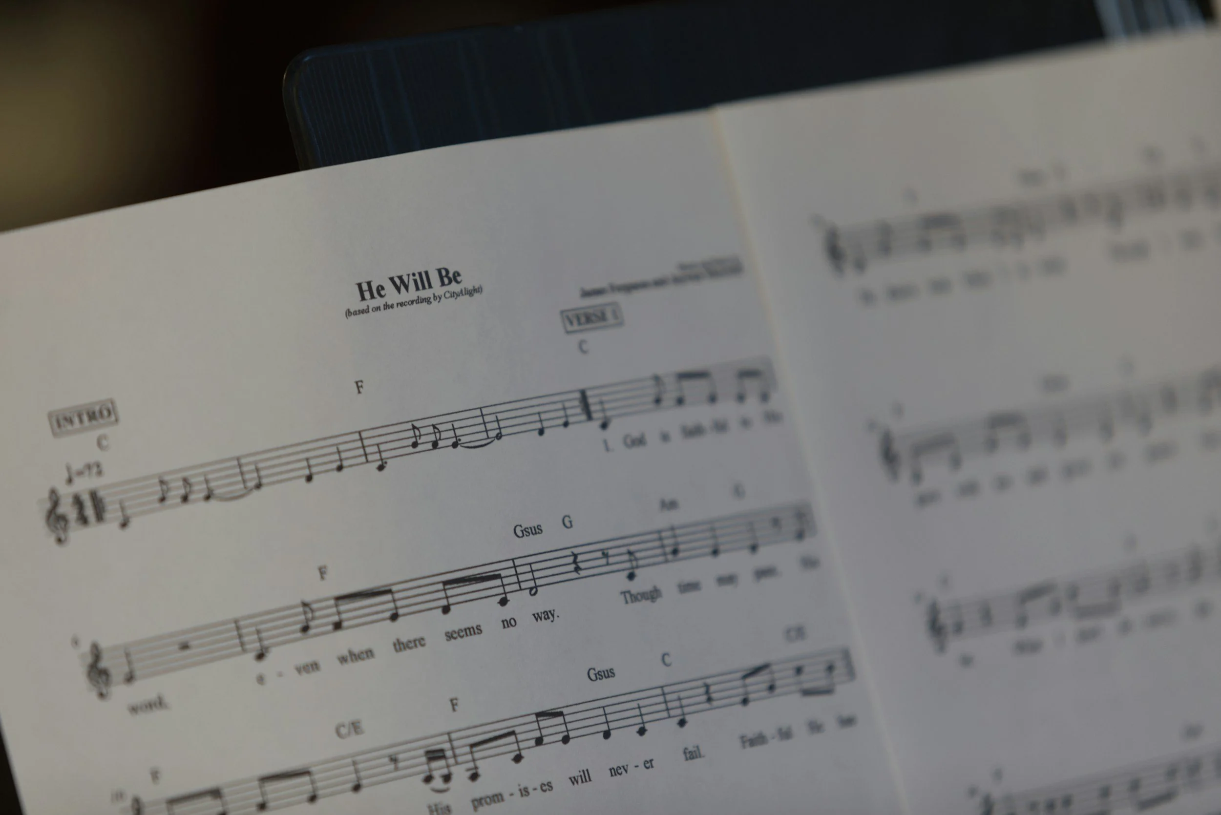 Close-up of printed sheet music titled “He Will Be,” with musical notation, lyrics, and guitar chords.