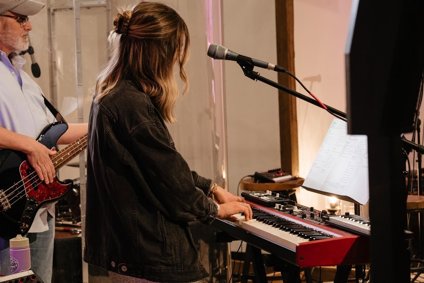 Singer playing a red electronic keyboard beside a bassist during a rehearsal