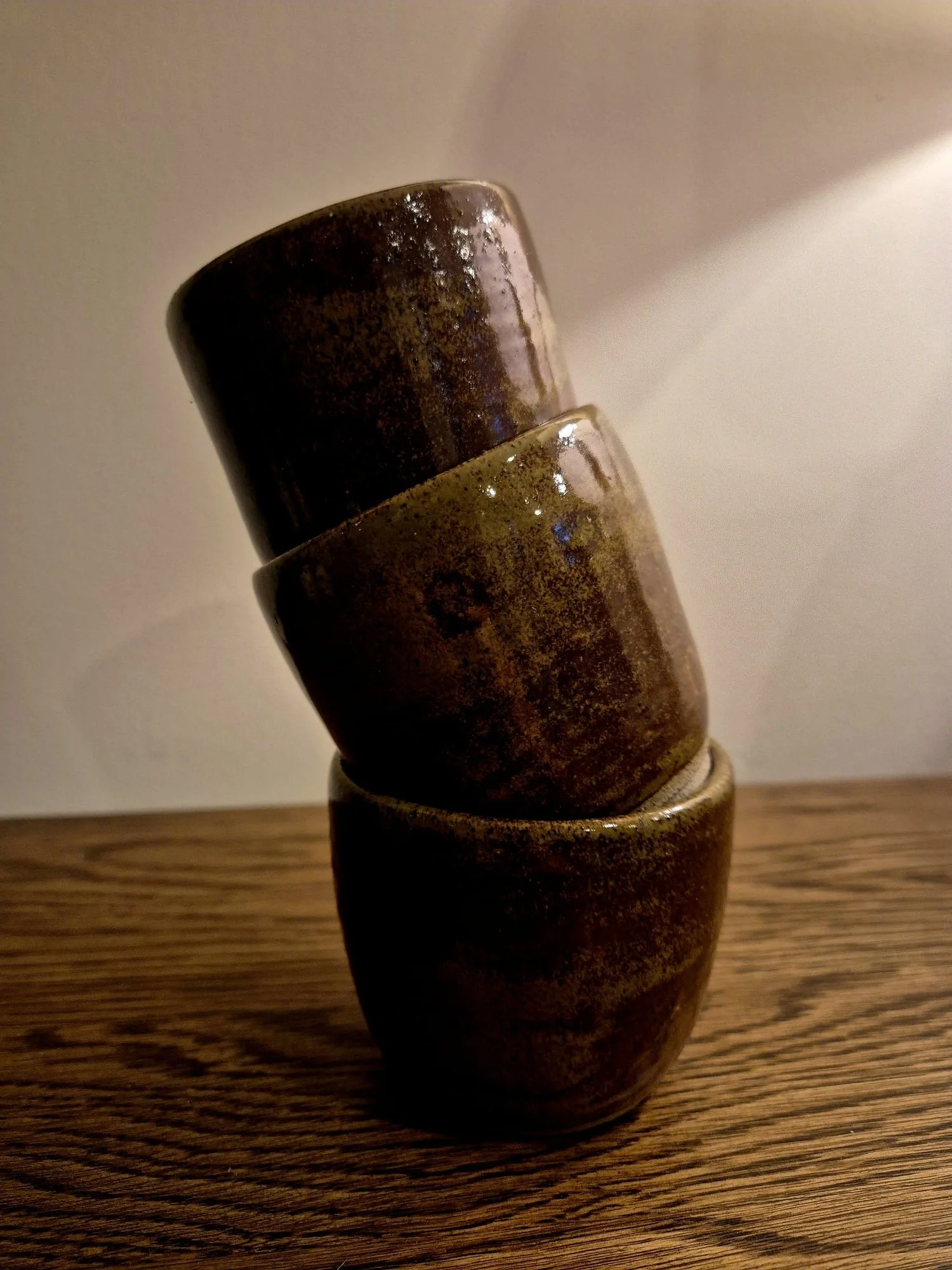 Stacked rustic brown ceramic cups on a wooden table