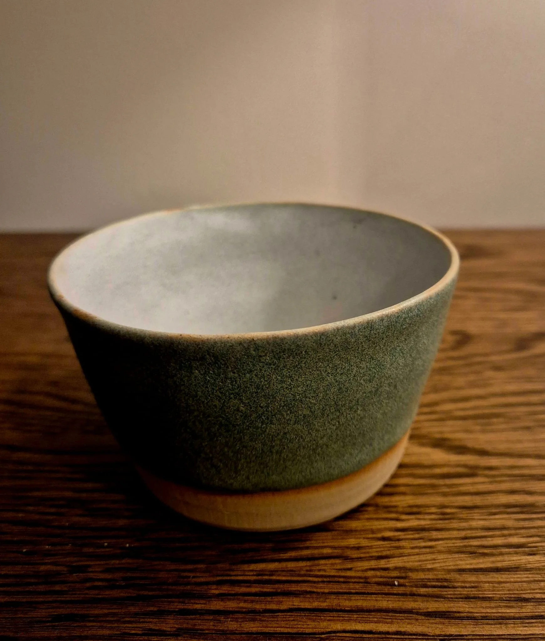 Empty green ceramic bowl on a wooden table