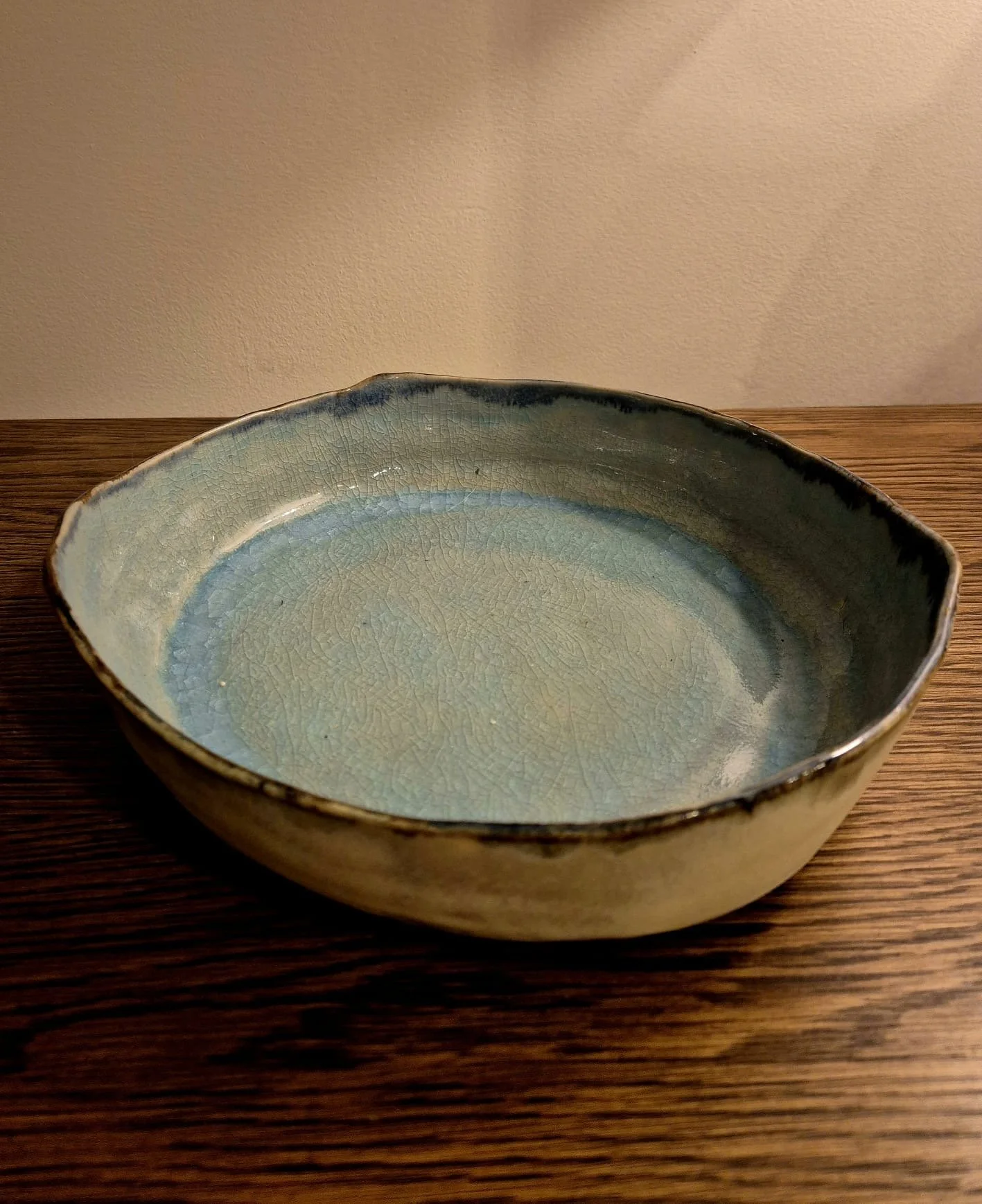 Handcrafted blue-green ceramic serving bowl on a wooden table