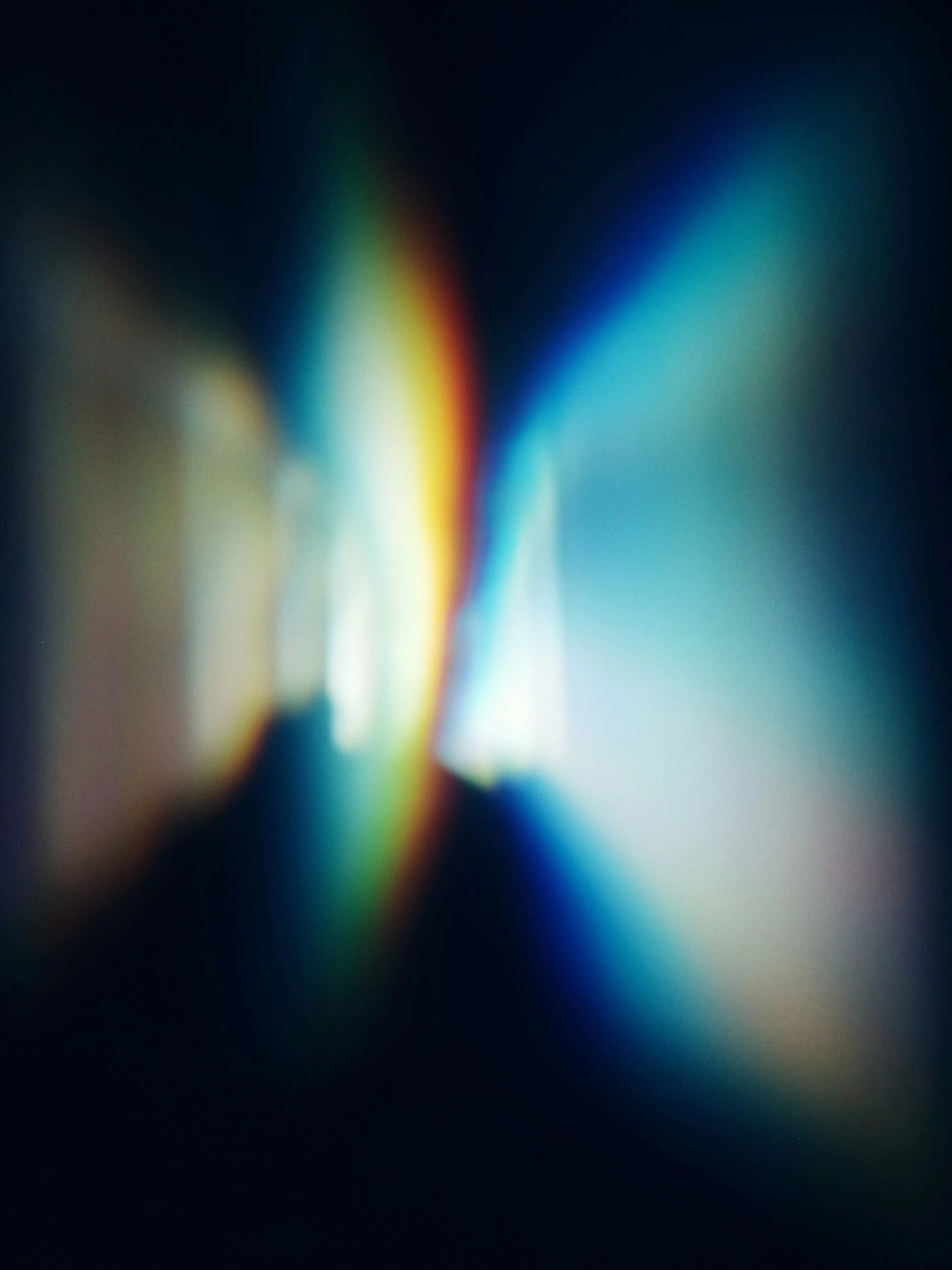 Abstract blurred multicolored light streaks in blue, teal, yellow, and orange on a dark background