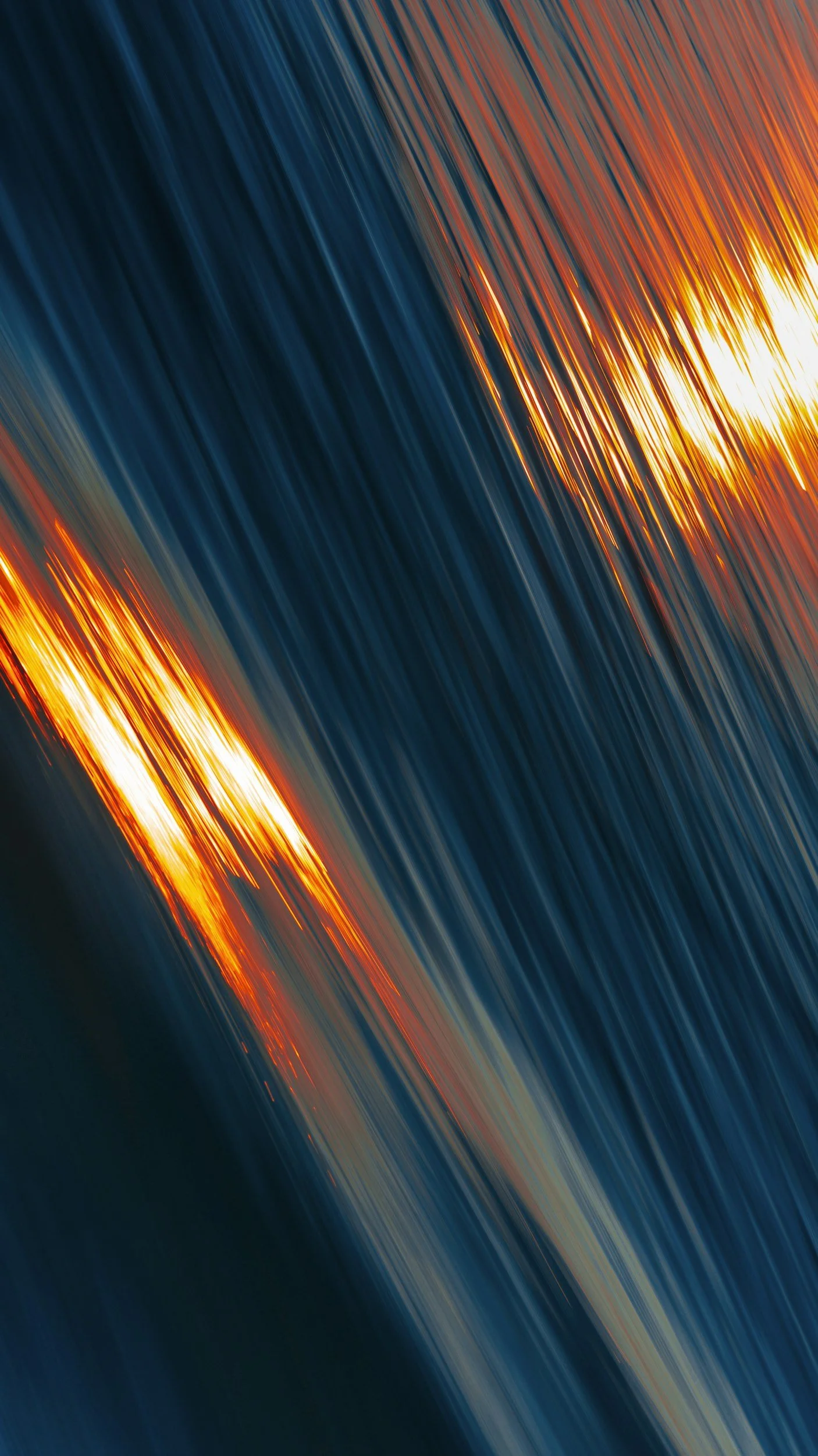 Abstract long-exposure light trails in vivid orange, white, and deep blue arcs