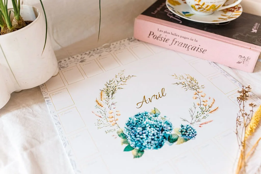Calendrier d’avril fleuri avec hortensias bleus, livre de poésie française, tasse à thé et plante en pot