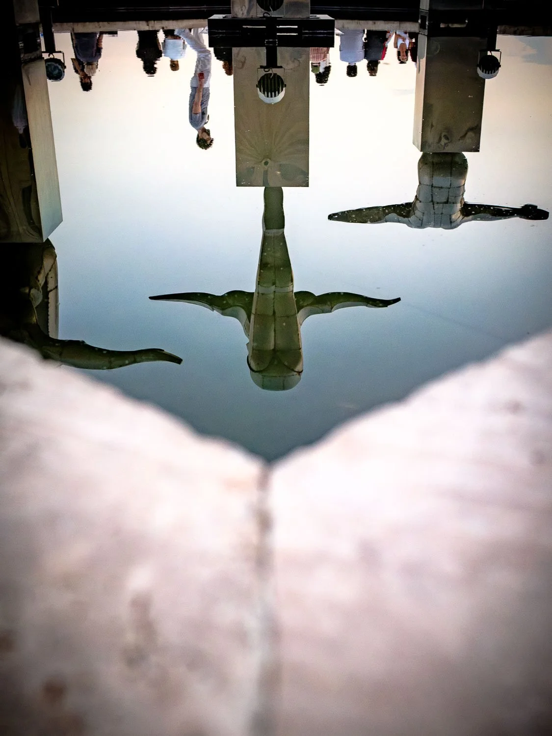 Upside-down underwater view of a scuba diver swimming beneath a boat, with people and equipment visible on the vessel above.