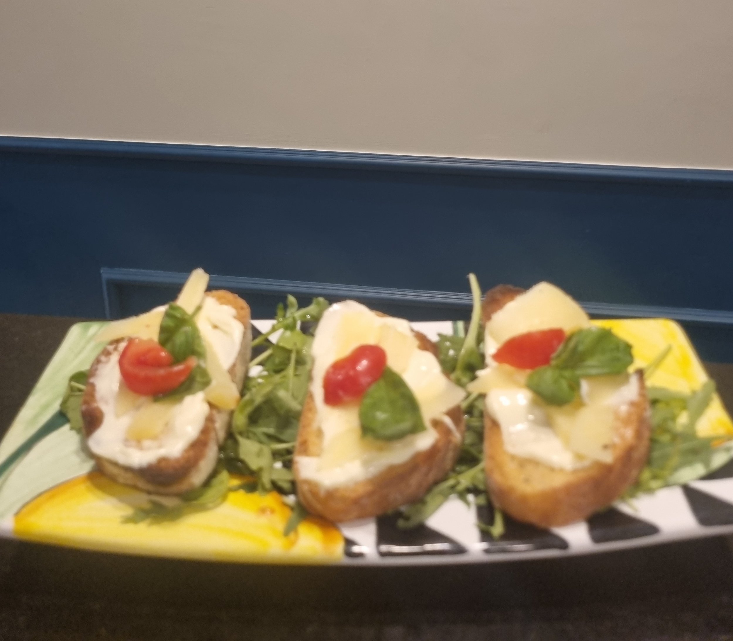 Piatto di crostini con mozzarella, pomodorini e basilico, serviti su un letto di insalata e verdure