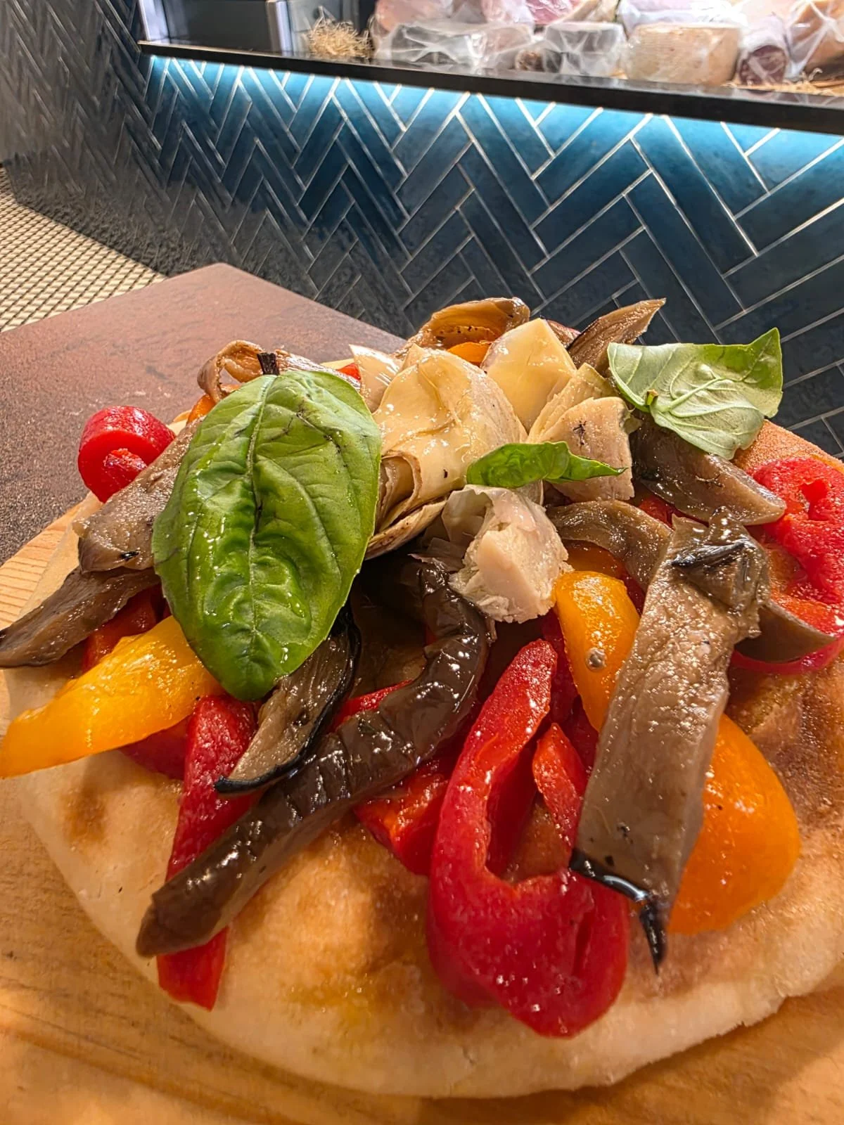 Pizza gourmet con verdure grigliate, funghi, pomodorini e basilico fresco