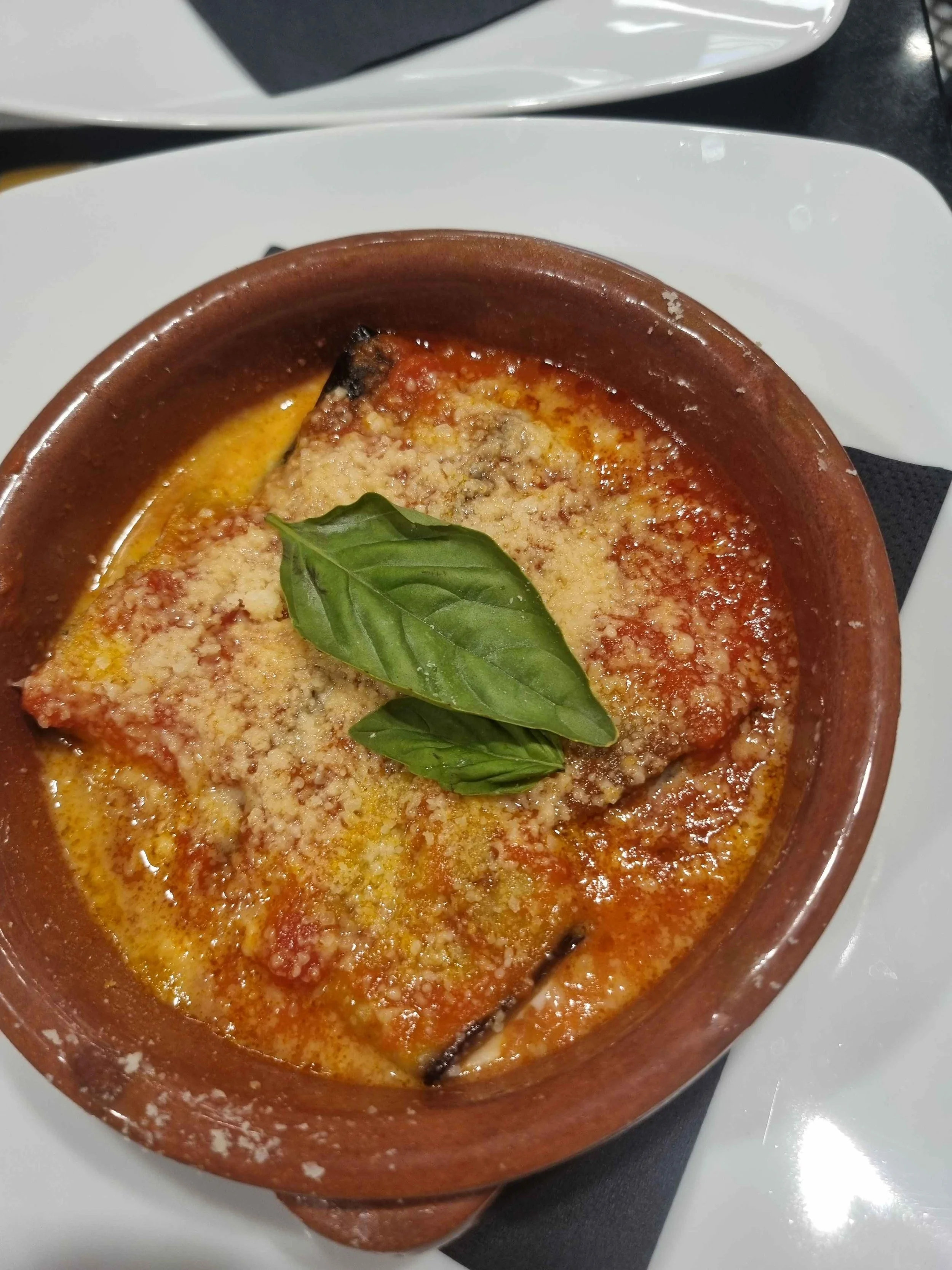 Pizza margherita con mozzarella filante e basilico fresco, servita in un tegame di terracotta