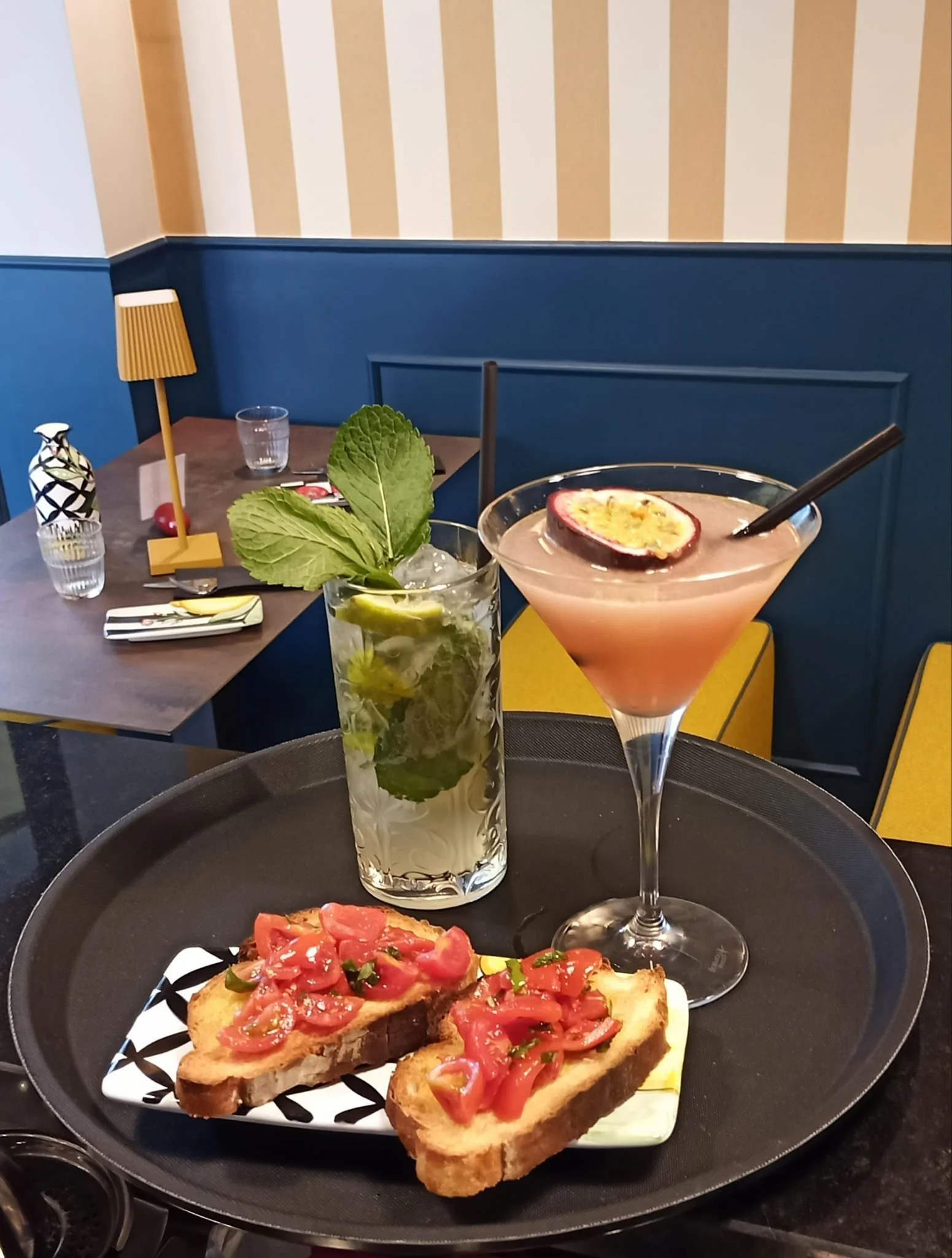 Tagliere con bruschette al pomodoro, cocktail alla frutta con passion fruit e bicchiere di mojito alla menta in un ristorante elegante.