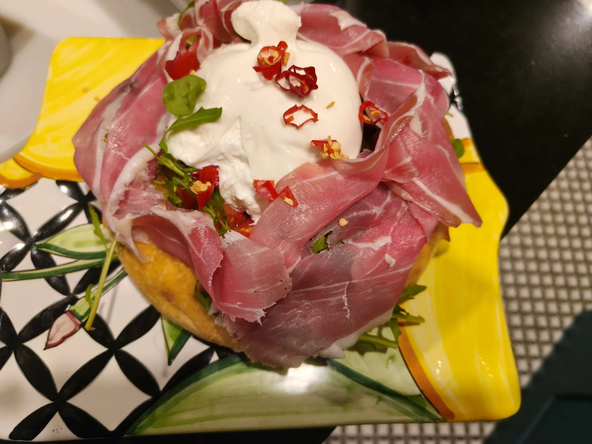 Piatto gourmet con burrata cremosa, prosciutto crudo, peperoncino fresco, rucola e fette di agrumi