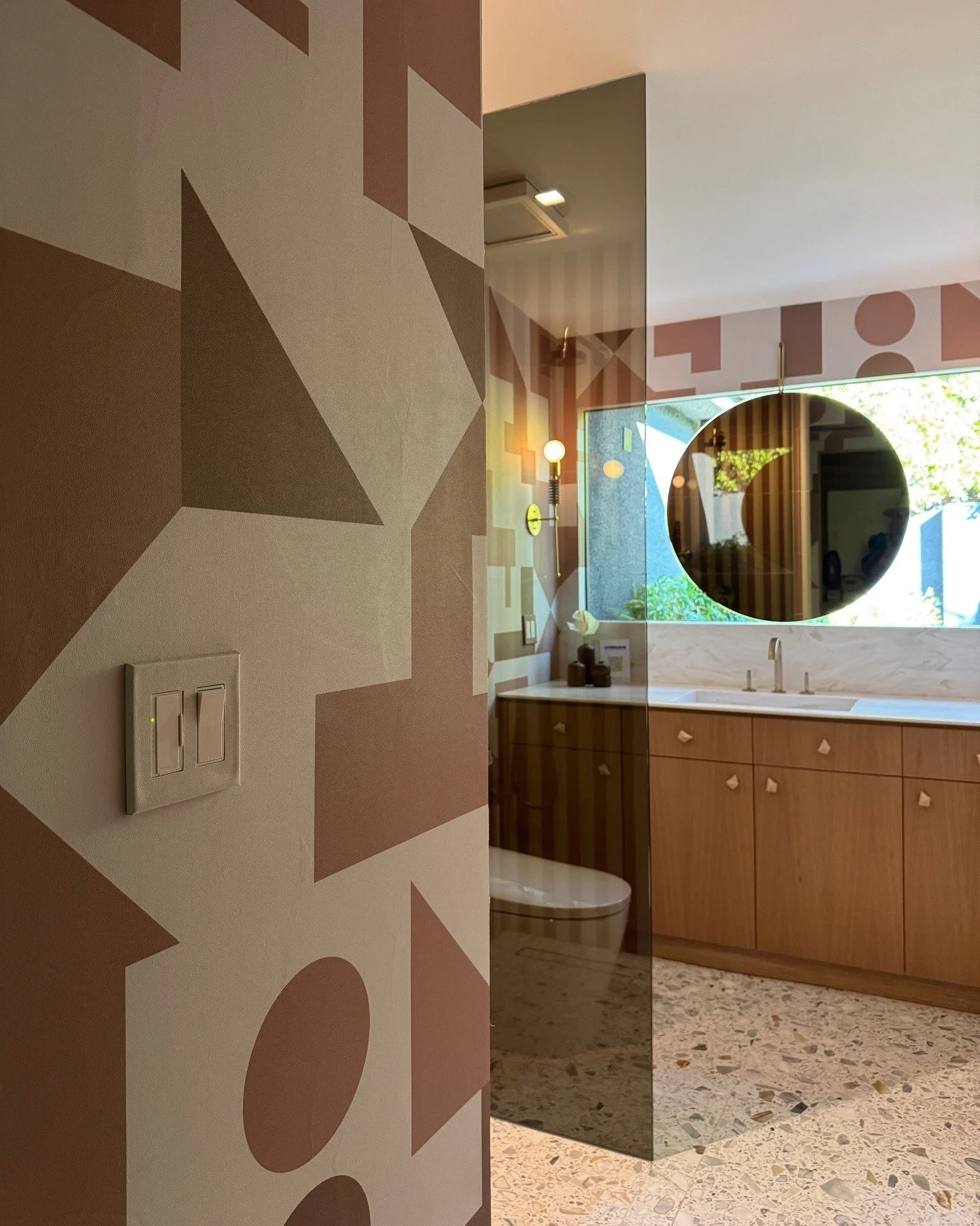 Bathroom doorway with geometric mural and a wood vanity