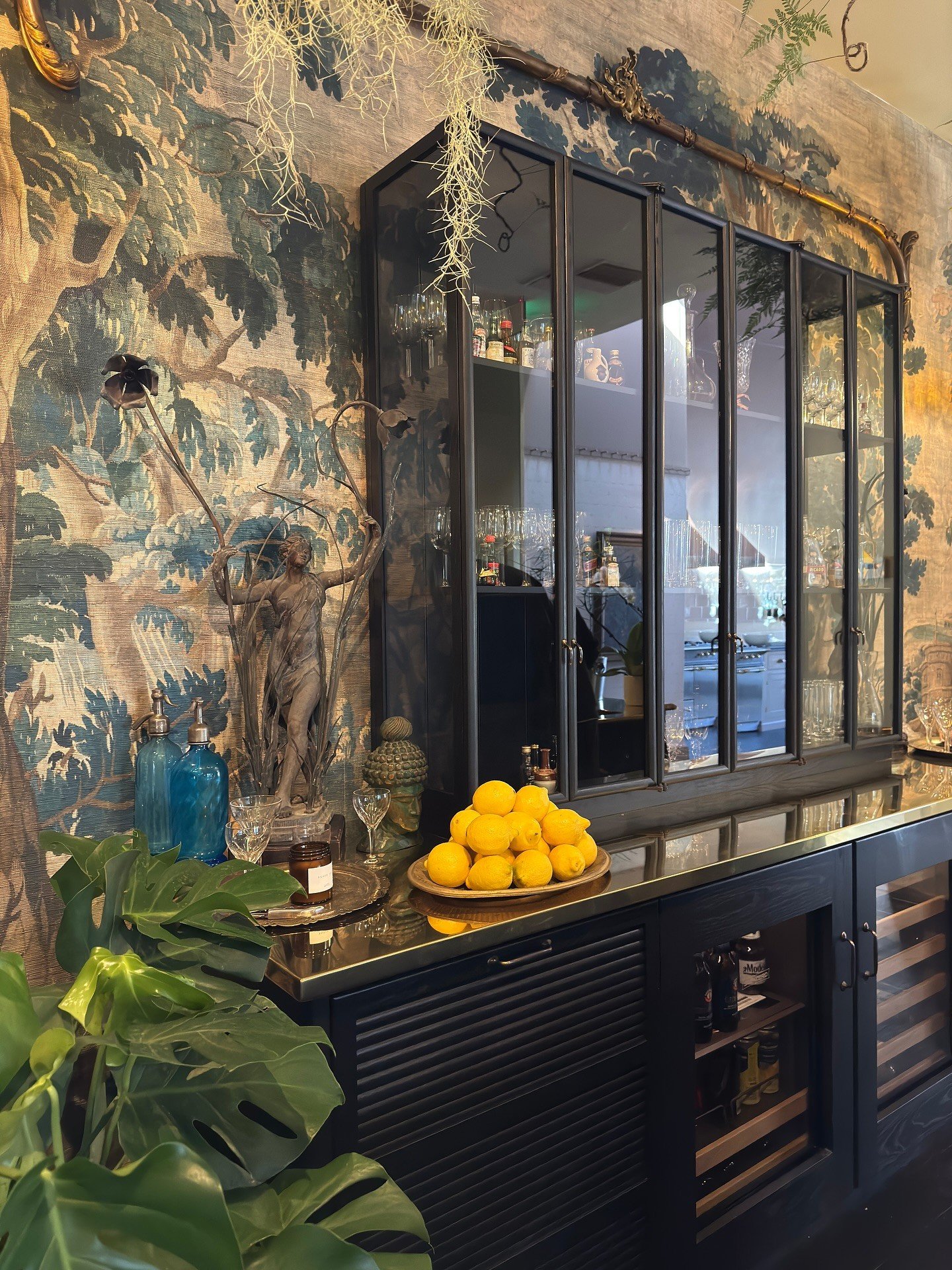 Dark glazed cabinet against richly patterned botanical wallpaper