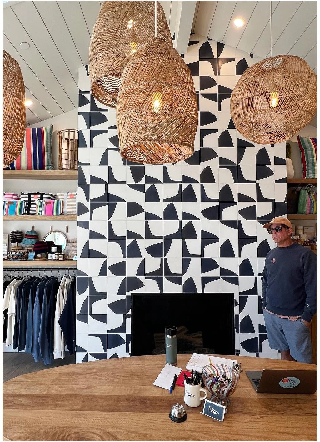 Motel reception desk beneath woven pendants and graphic patterned wallpaper