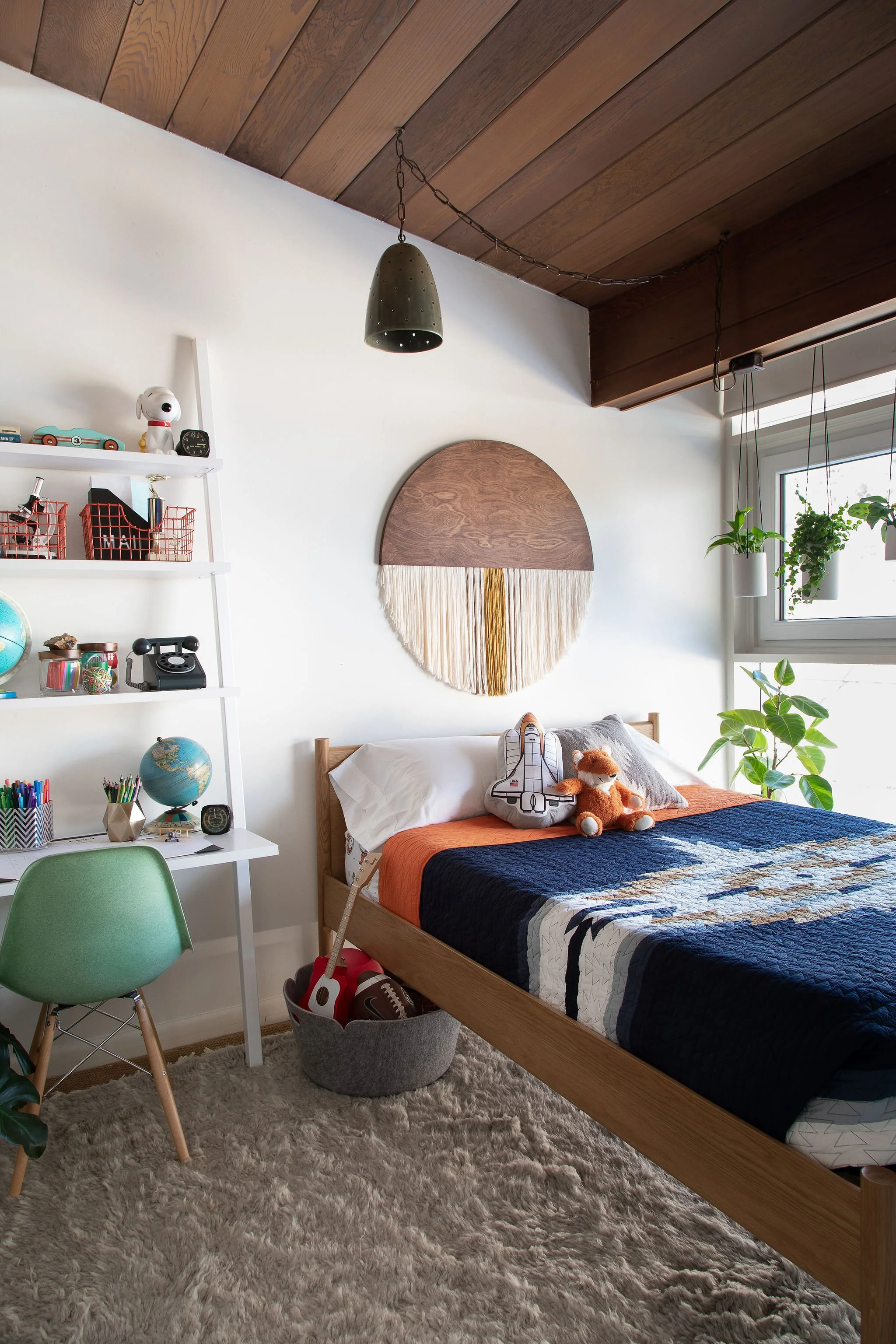 Bedroom with a wood ceiling, blue bedding, and a round wall hanging.
