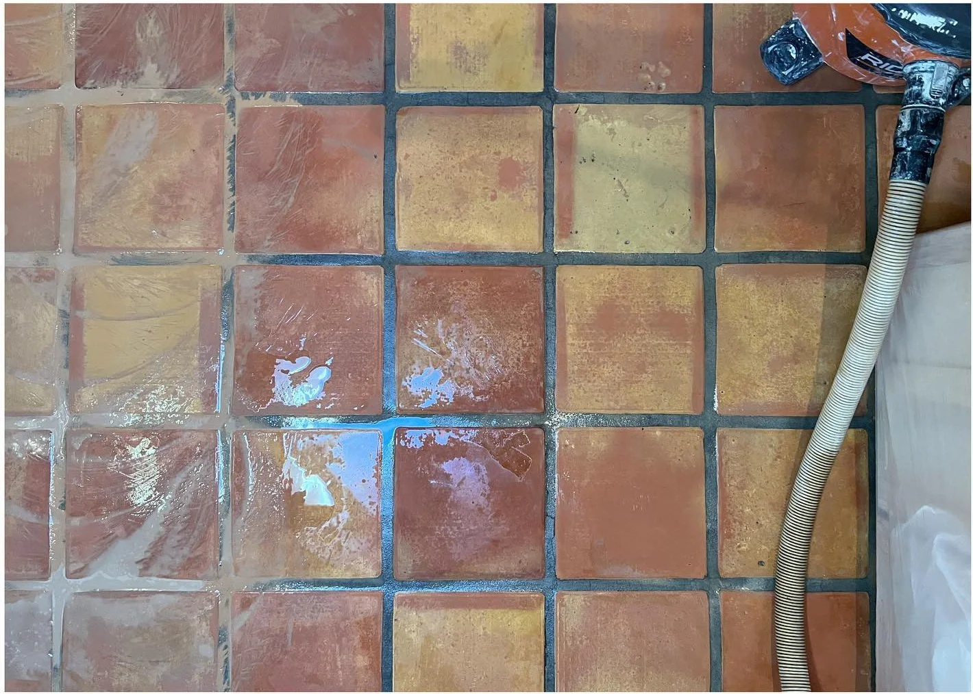 Floor restoration in progress with a wet cleaning tool over terracotta tiles