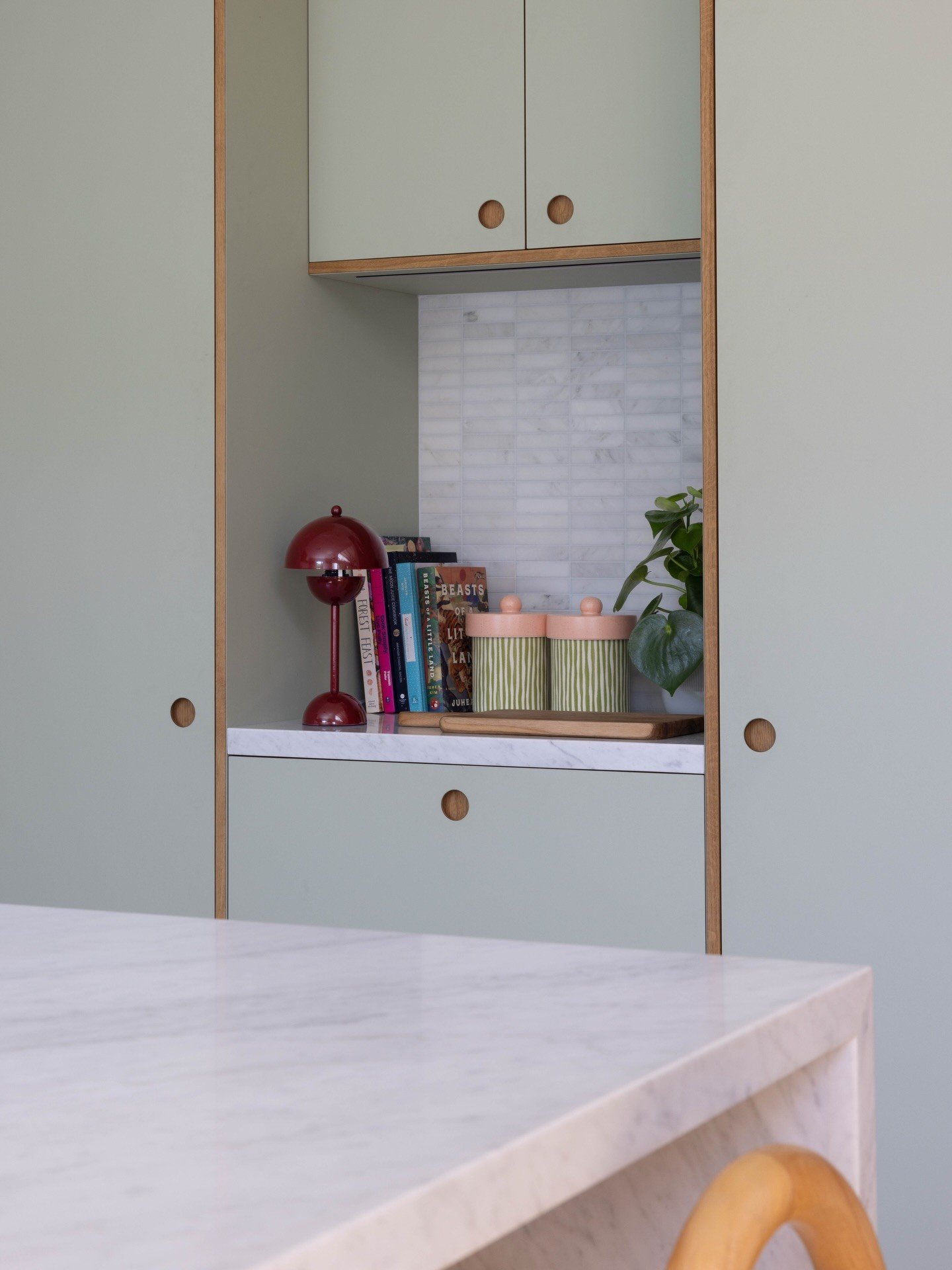Pale green pantry doors framing a counter with a red lamp