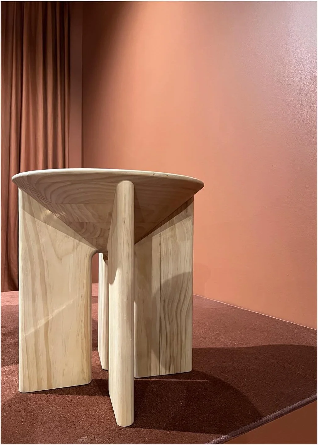 Small angular wood side table against a warm pink wall