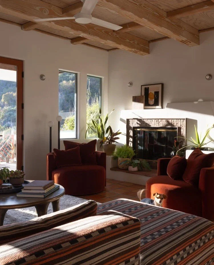 Orange lounge chairs and low patterned seating beneath wood beams