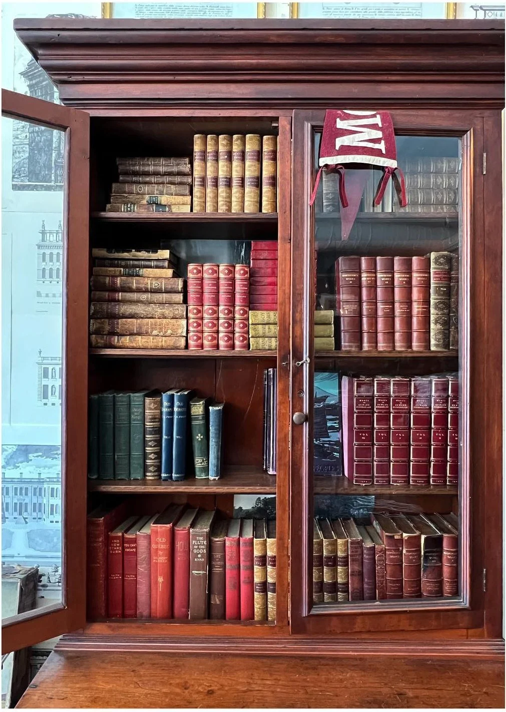Tall wood bookcase filled with red and brown vintage books