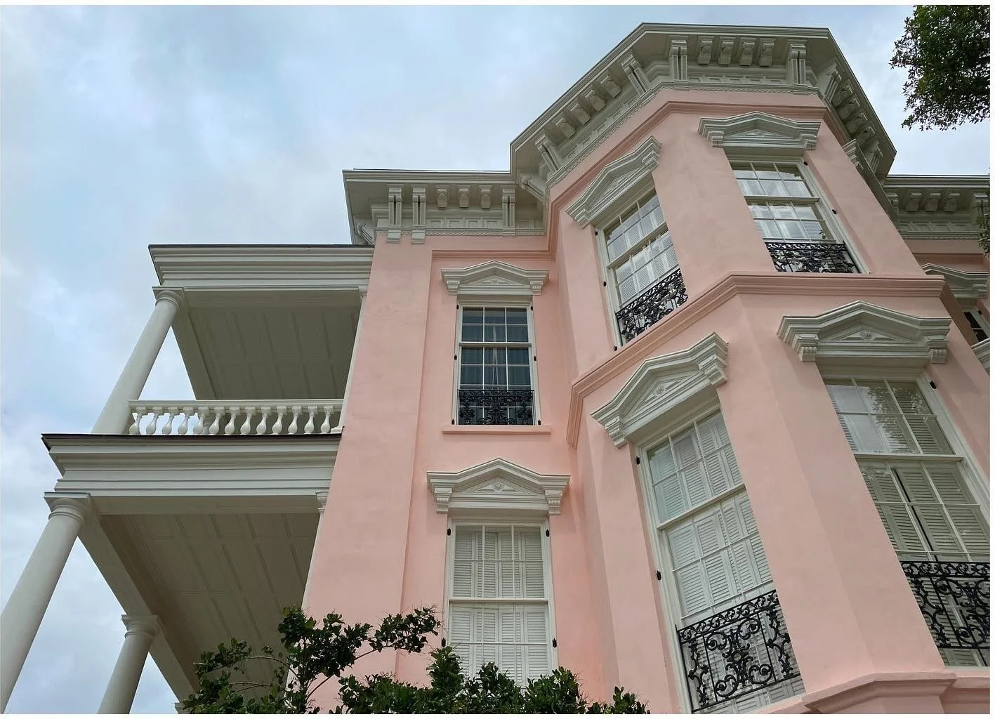 Pink historic house with projecting bay windows and decorative cornice